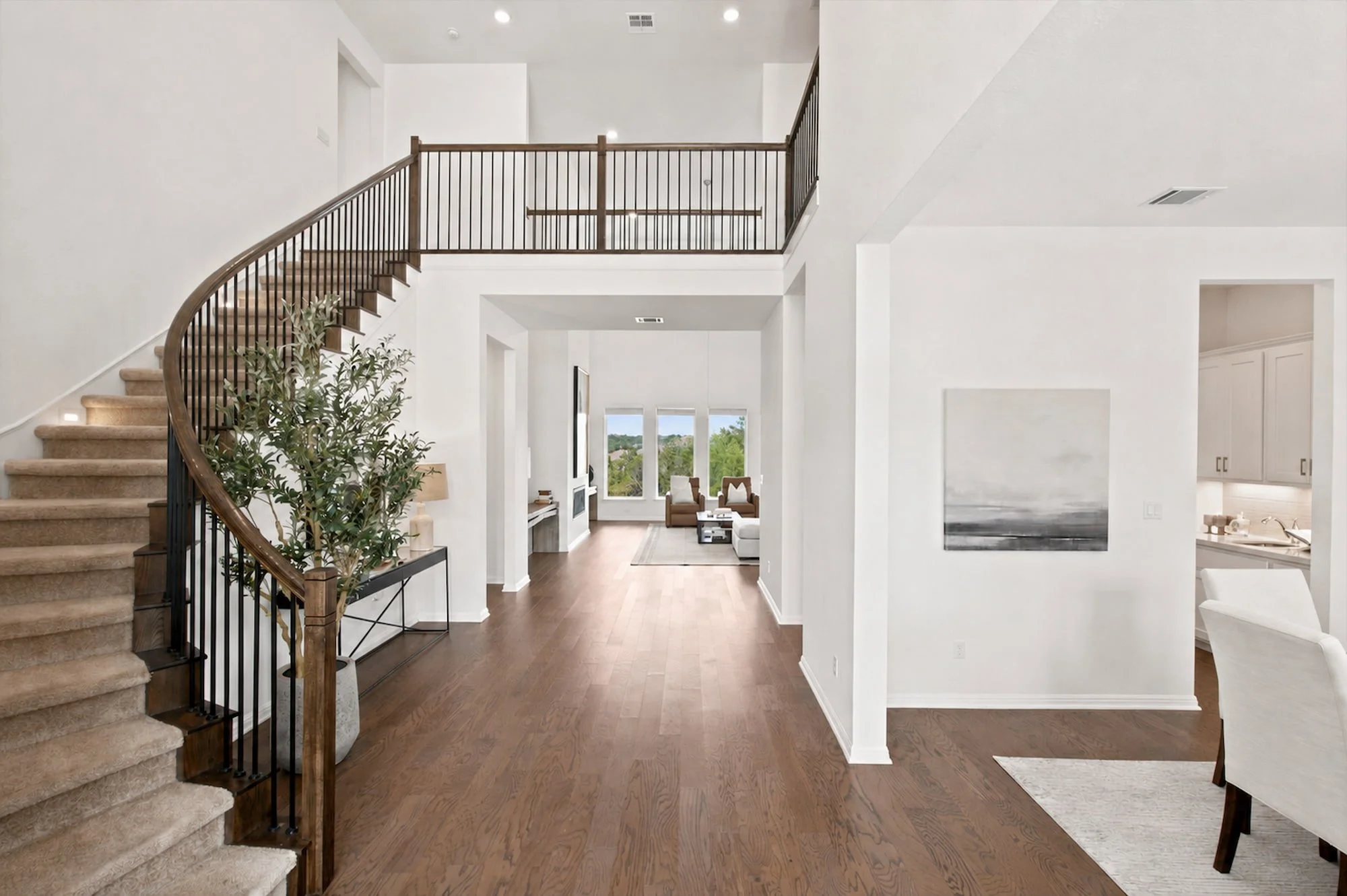 A curved staircase sweeps toward an open loft, opening the foyer to the living space below.