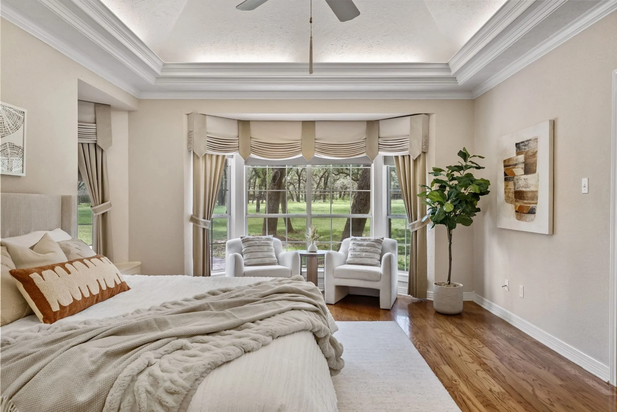 Primary suite with a sitting area and large windows overlooking mature oak trees.