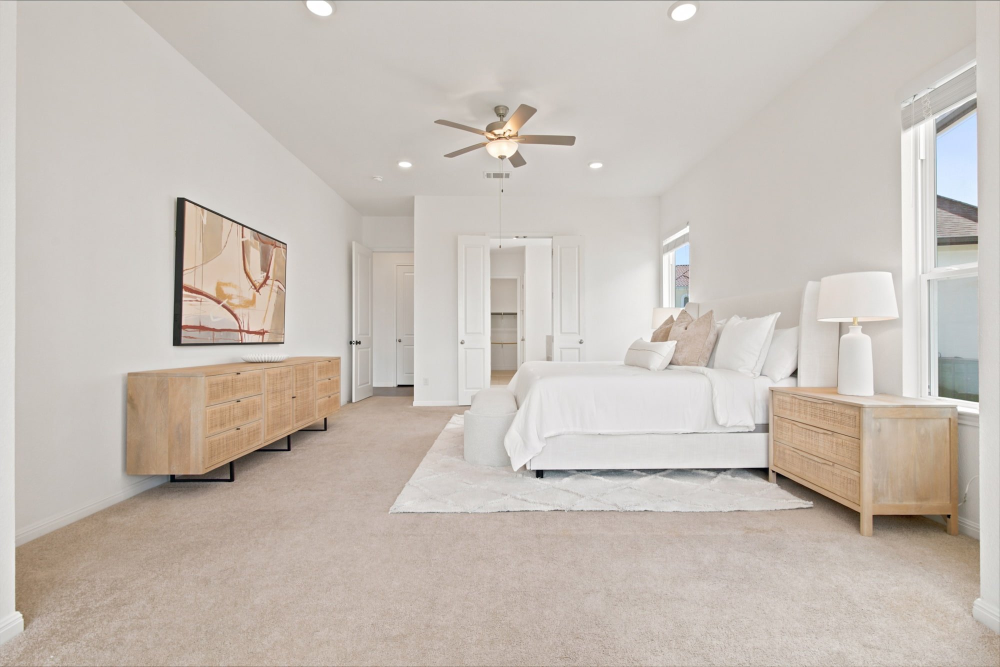 A floating dresser and open closet doors line the spacious primary bedroom.