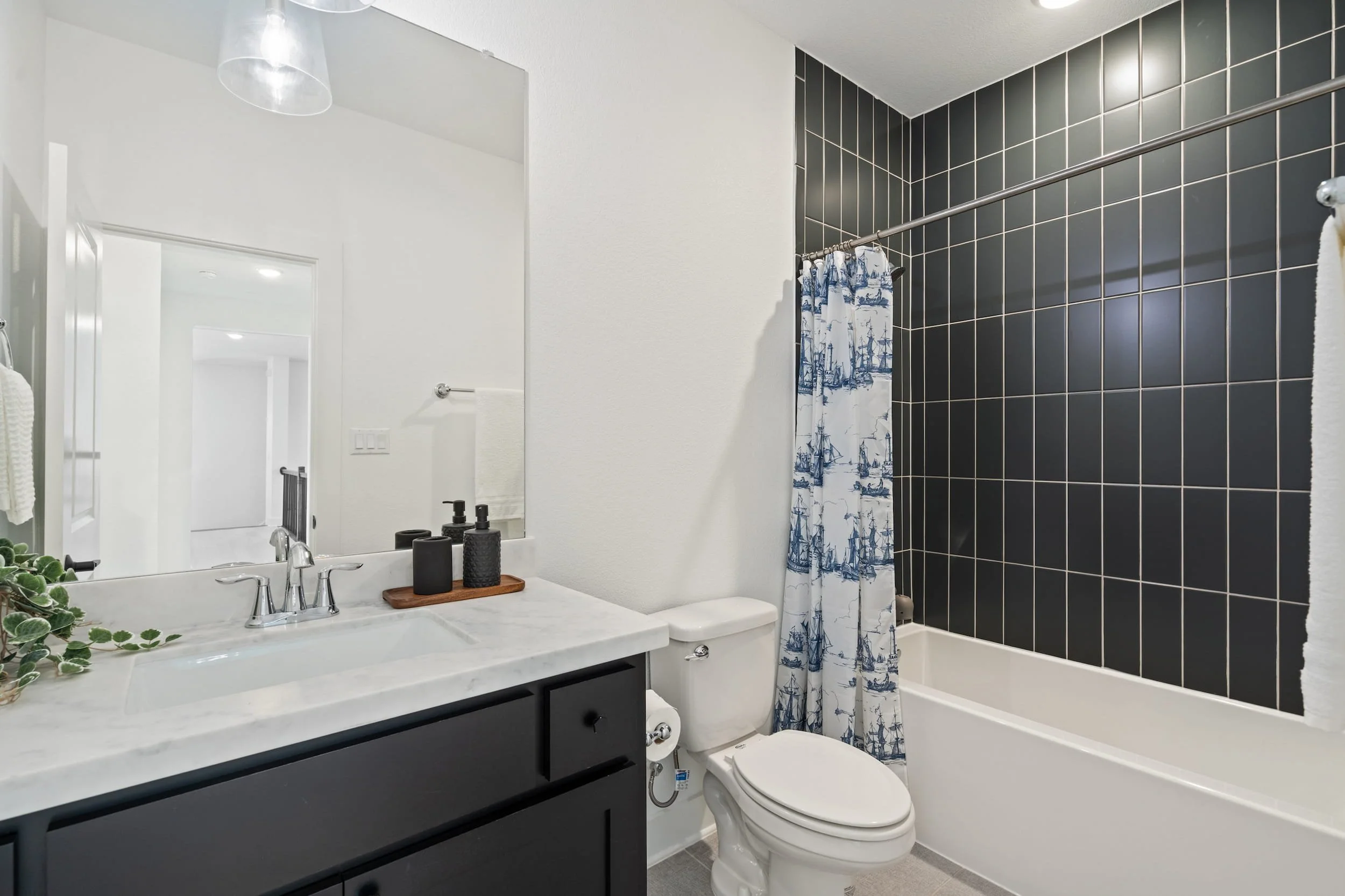 Austin bathroom with black tile shower, marble vanity, chrome fixtures, clean modern staging.