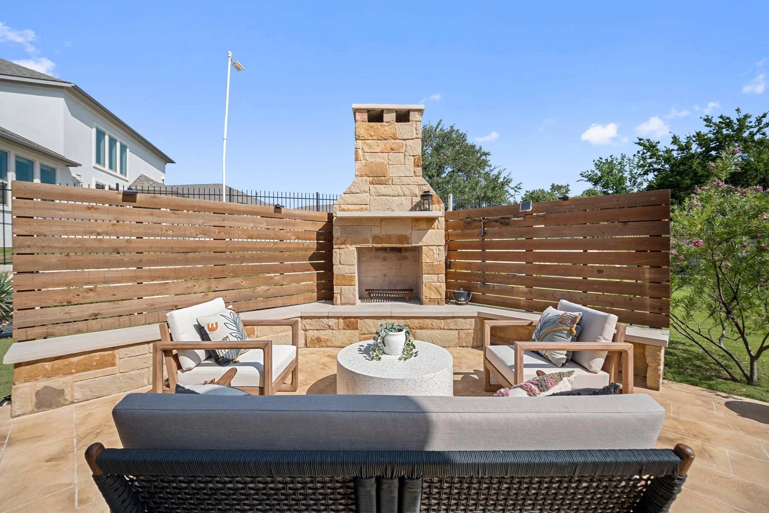 Austin backyard patio with stone fireplace, wood privacy fence, lounge seating, staged outdoor living for entertaining.