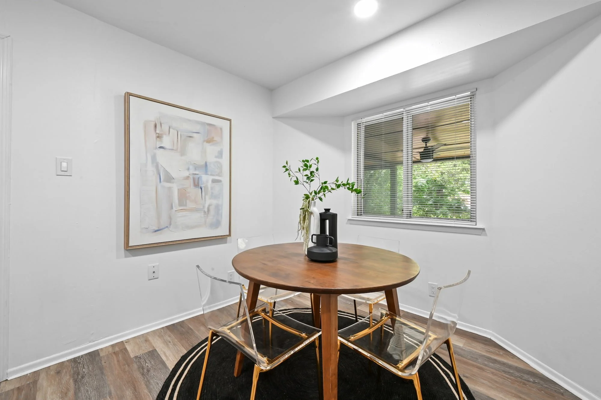 Clear acrylic chairs pull up to a round wood table in this sunlit breakfast nook.