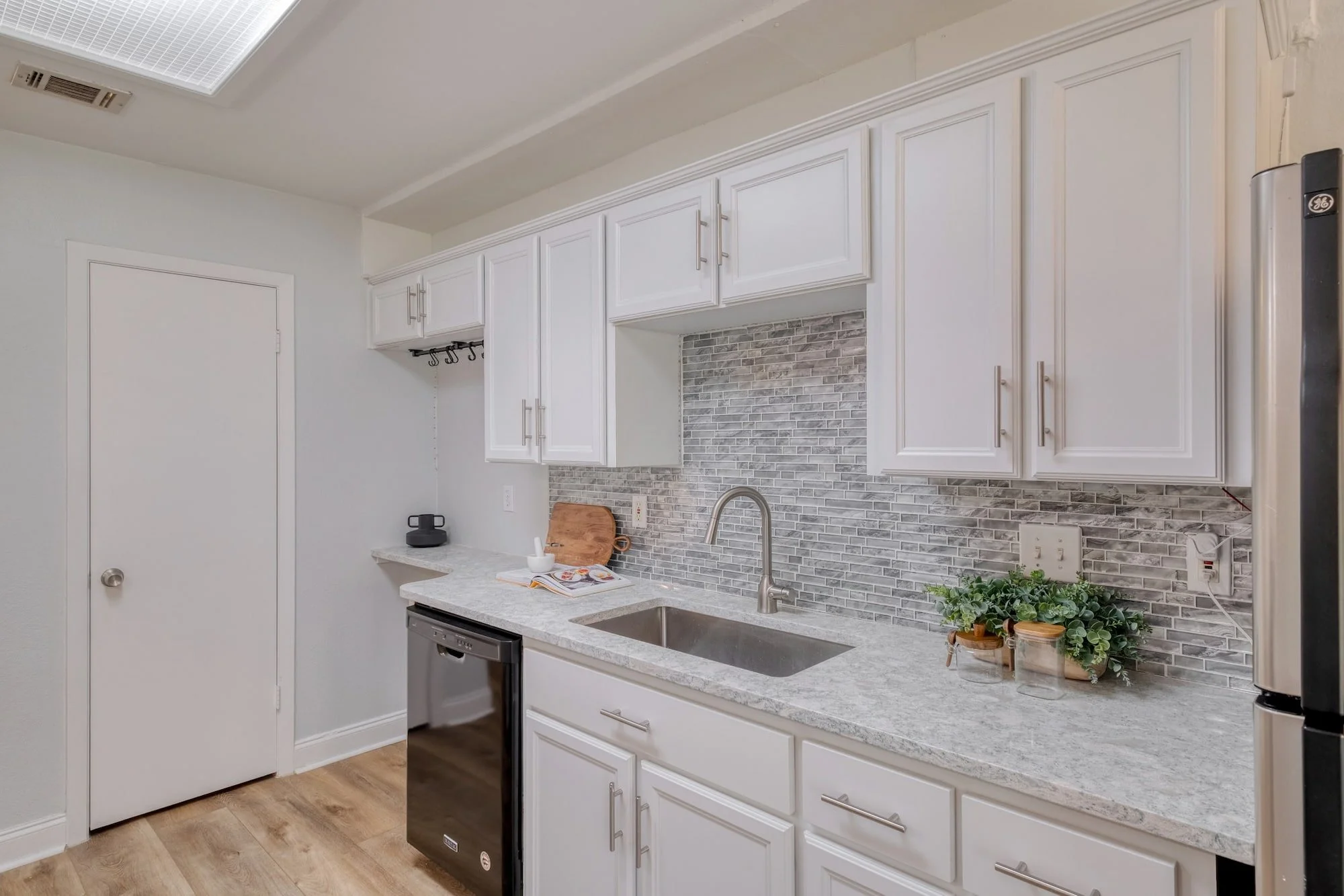Updated kitchen with extensive cabinetry, quartz-look countertops, and a modern mosaic tile backsplash.