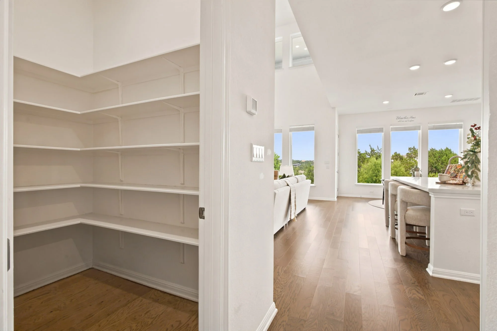Open shelving lines the walk-in pantry, just off the sunlit kitchen and living space.