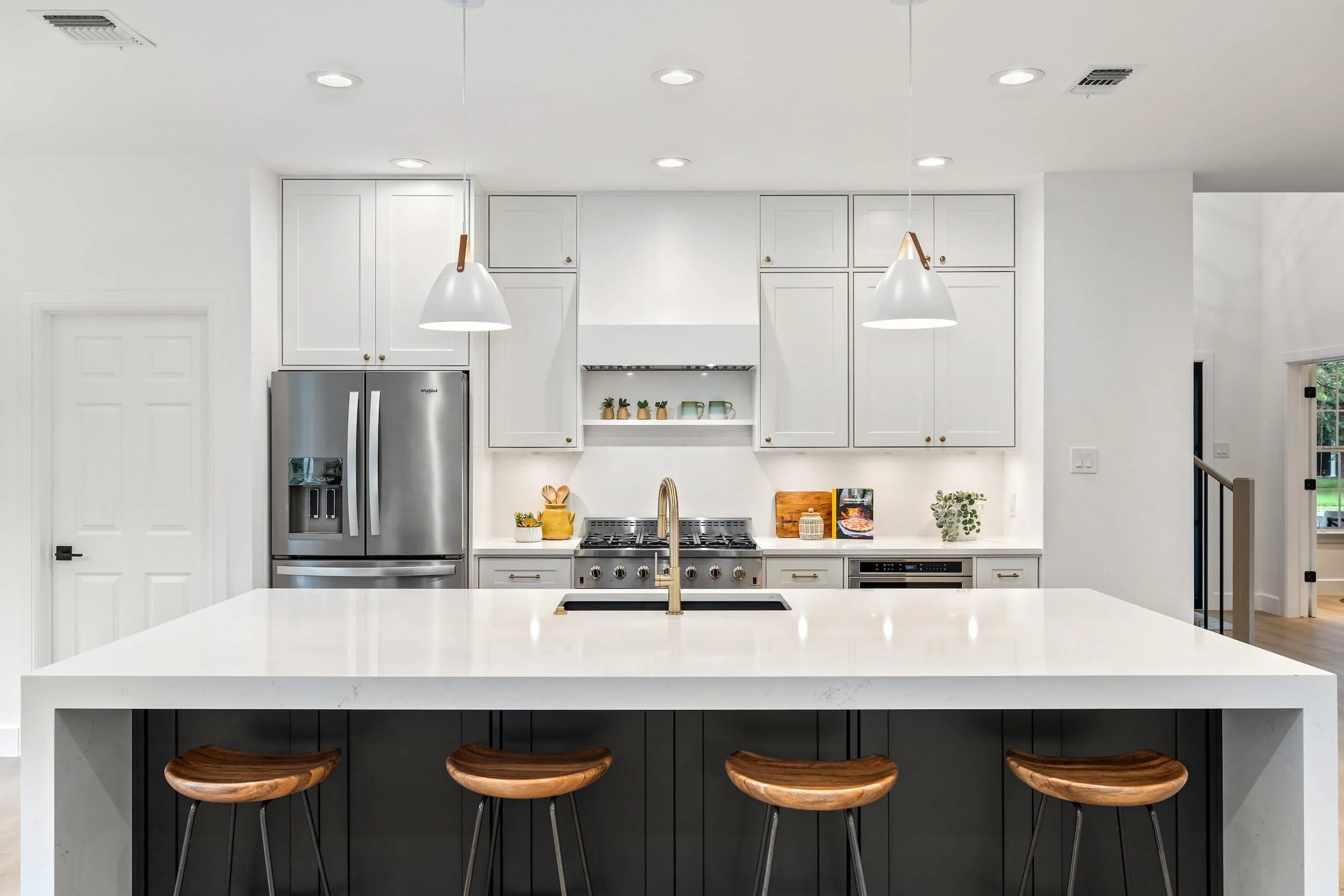 Modern kitchen with large island, wood bar stools, white cabinets, and stainless steel appliances, Austin TX