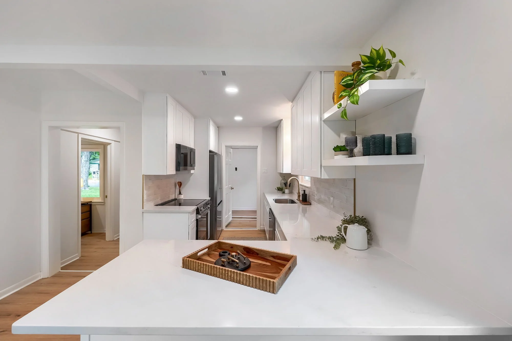 Bright, renovated kitchen with quartz countertops, custom cabinetry, and open shelving.