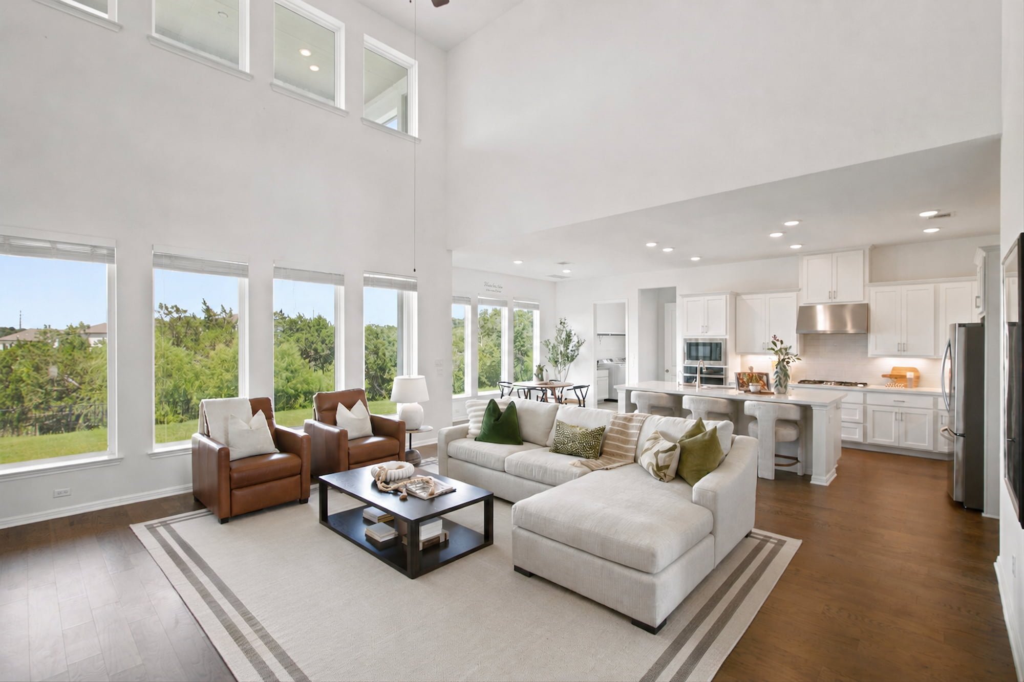 A sectional and leather chairs open onto the kitchen in this bright, two-story great room.