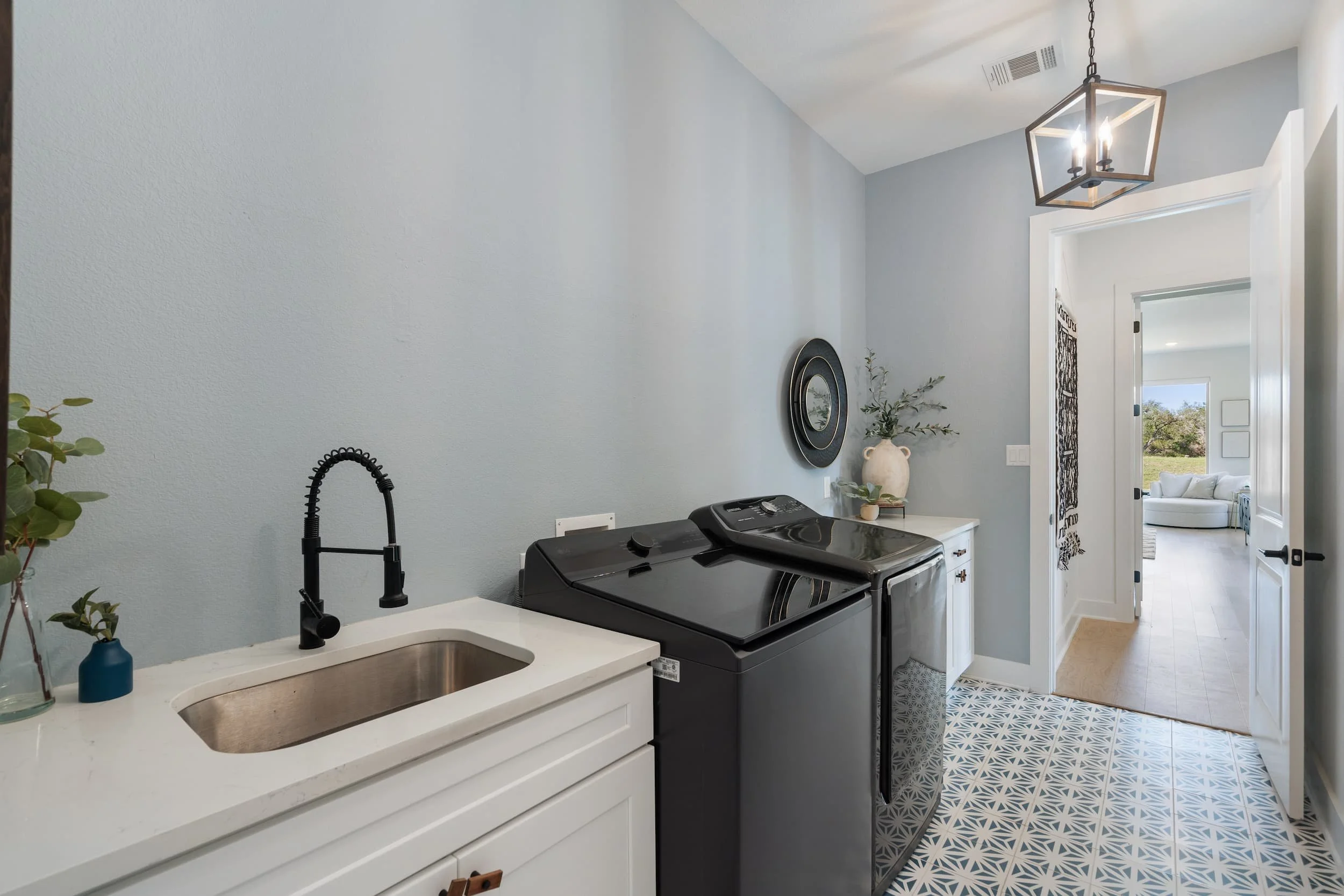 Laundry space in Austin featuring farmhouse sink, sleek appliances, geometric tile, neutral tones, functional design.