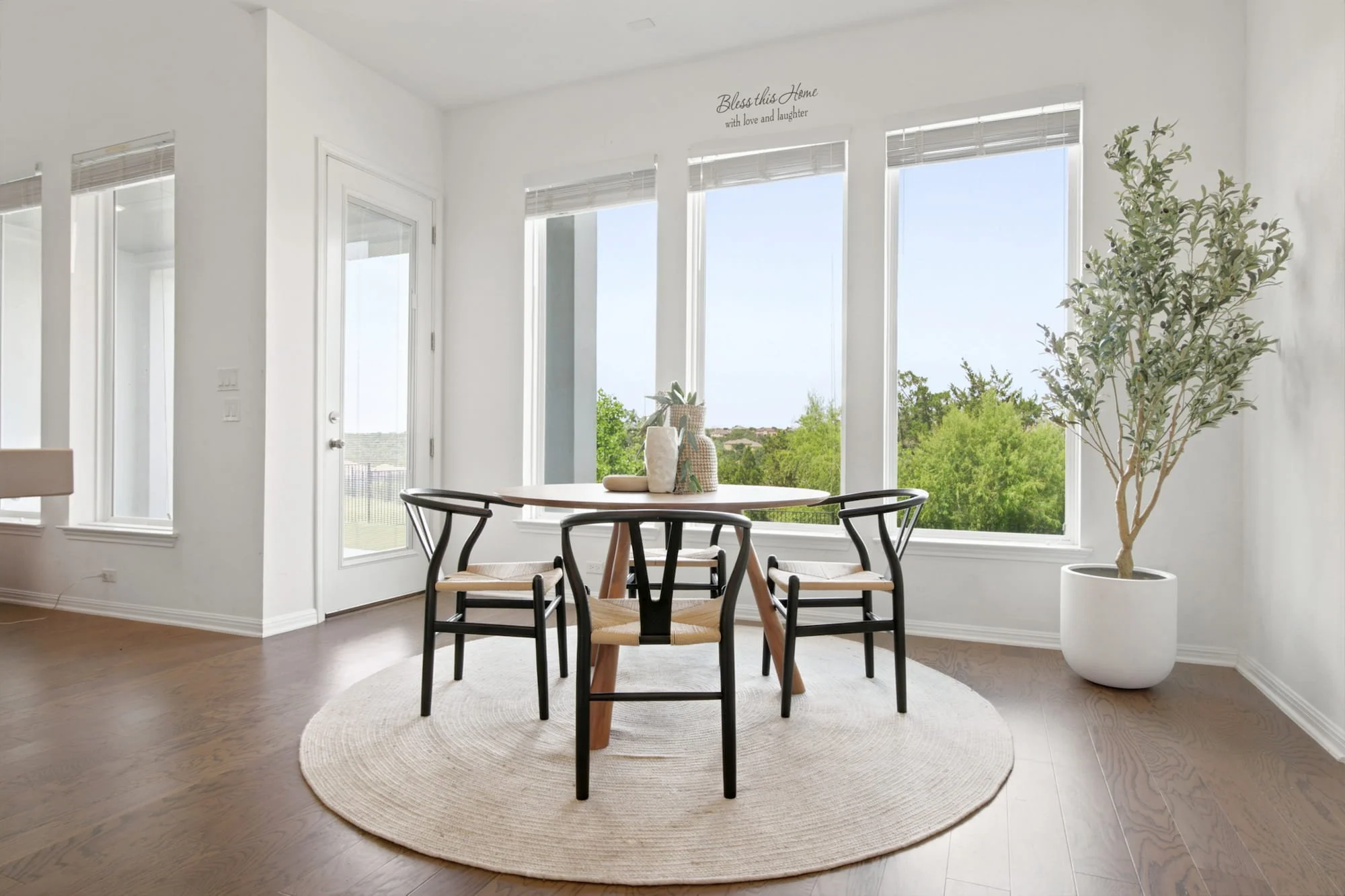 Wishbone chairs circle a round table in a light-filled breakfast nook overlooking the backyard.
