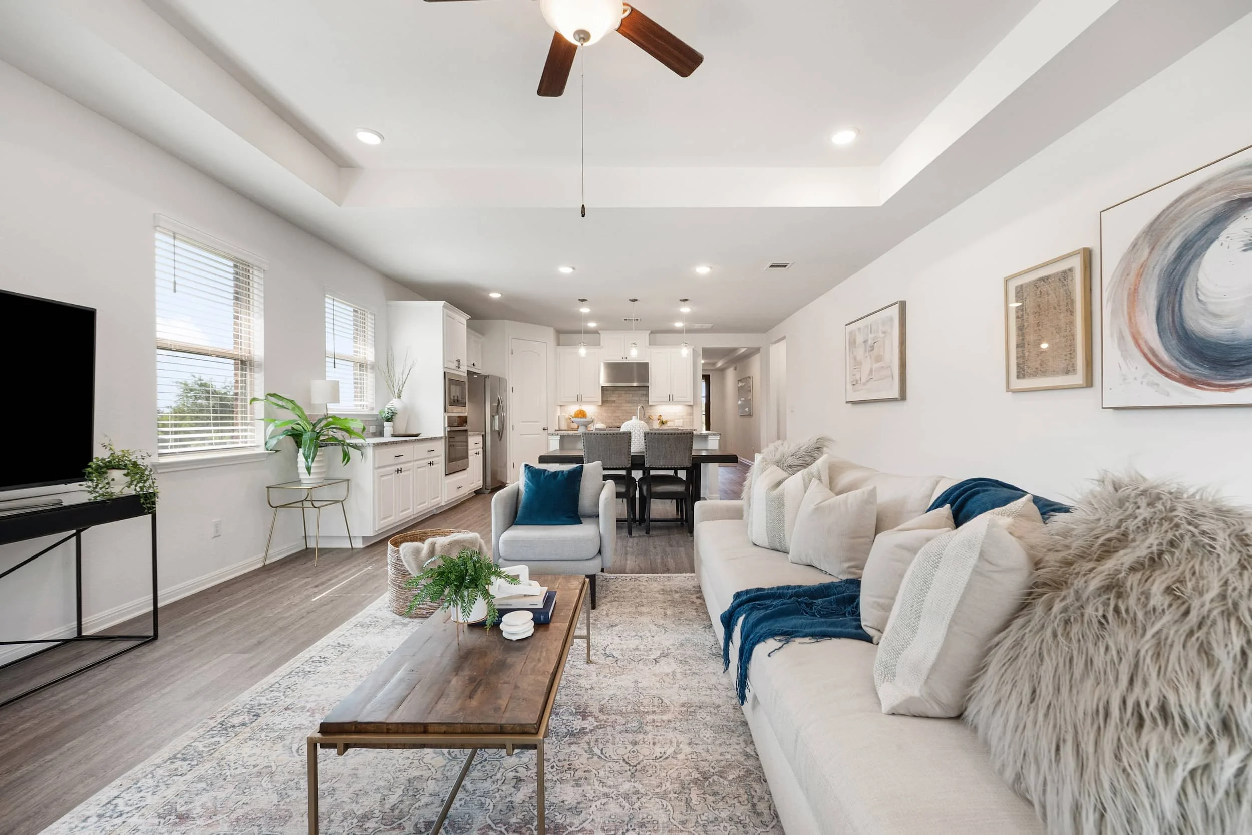 Elegant open concept living room staging with a tray ceiling, neutral sofa, wood coffee table, and vintage style rug.