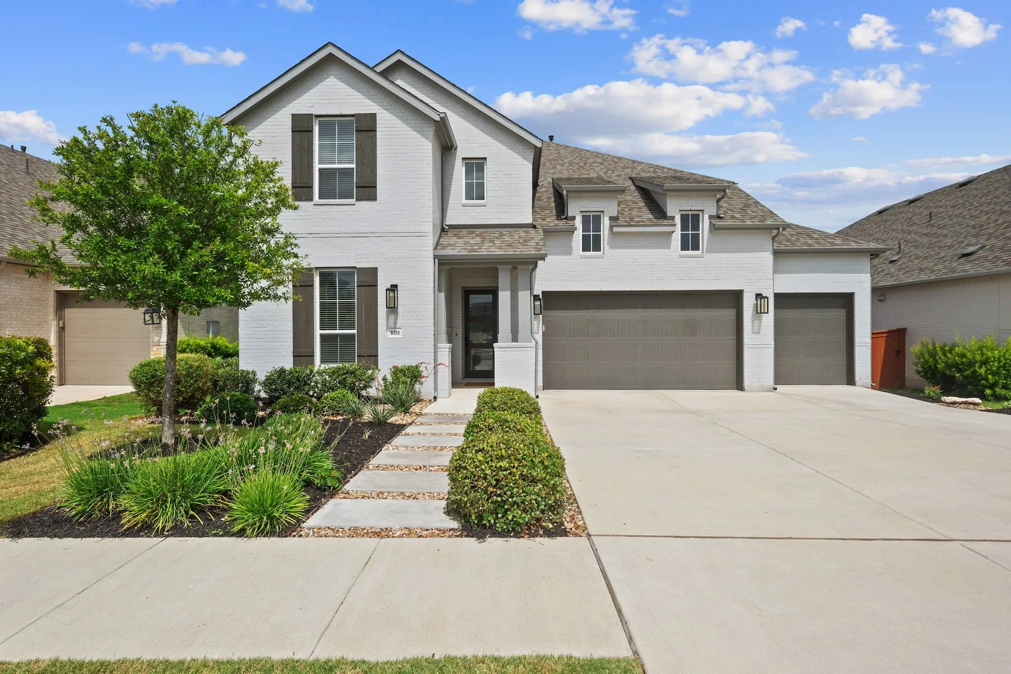 Luxury Leander home with painted brick exterior, landscaped entry, and three-car garage