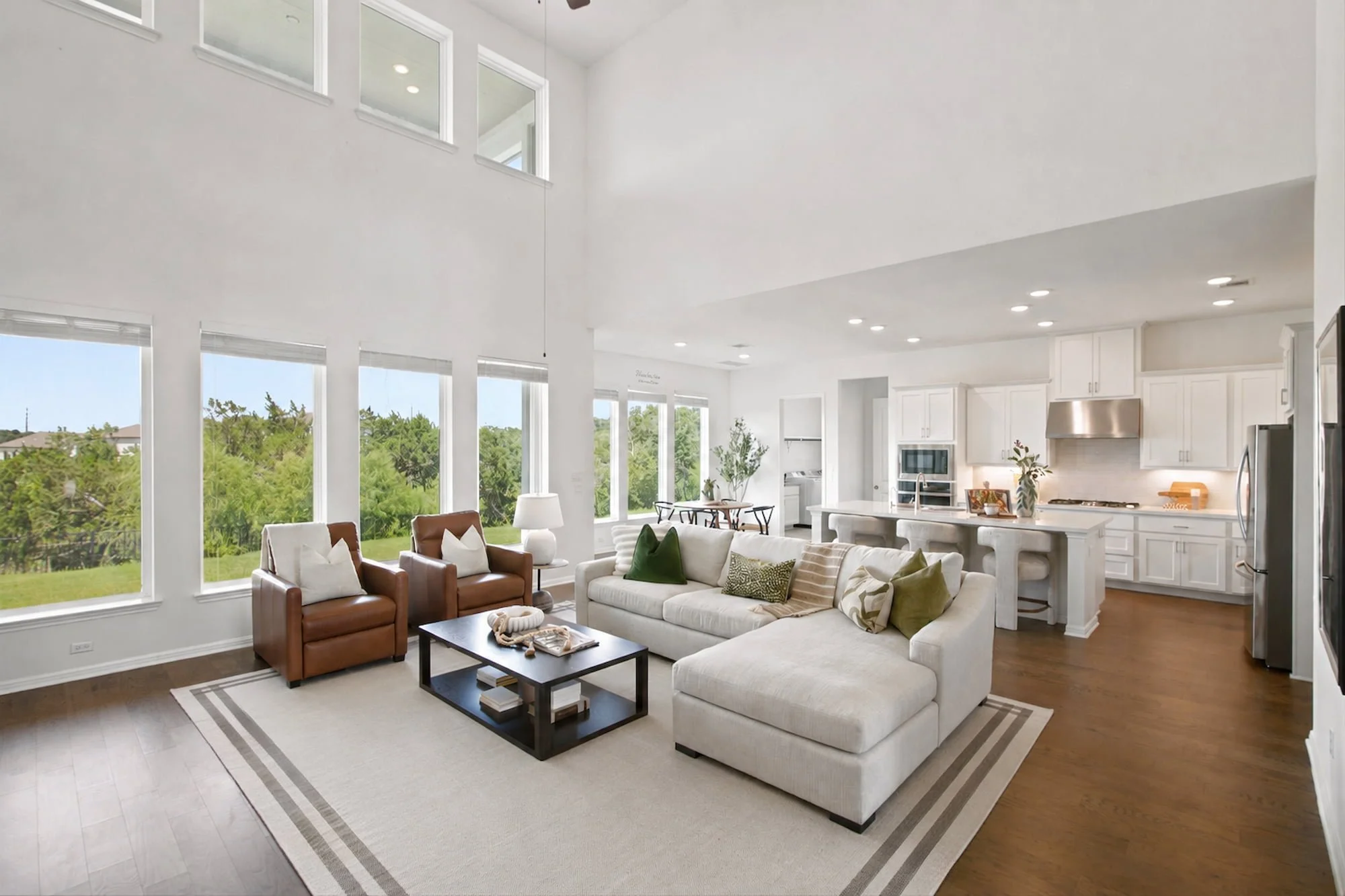 A sectional and leather chairs open onto the kitchen in this bright, two-story great room.