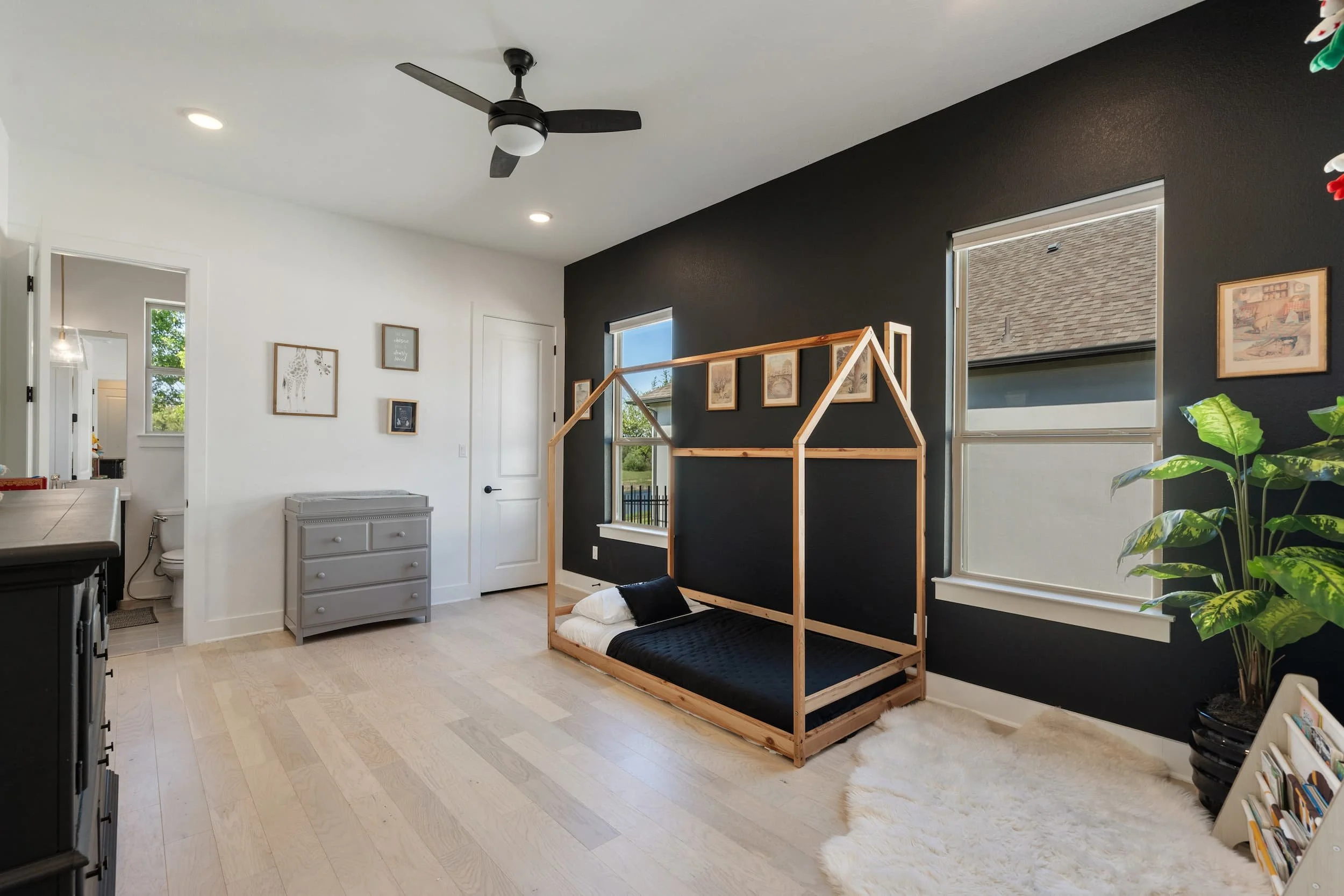 Modern child bedroom in Austin featuring Montessori house bed frame, contrast wall, simple styling, cozy space.