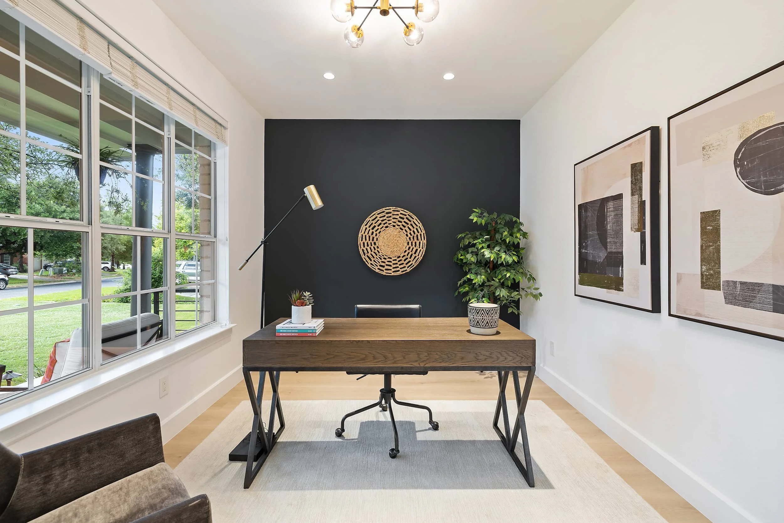 Bright home office with wood desk, dark accent wall, large window, and modern decor.