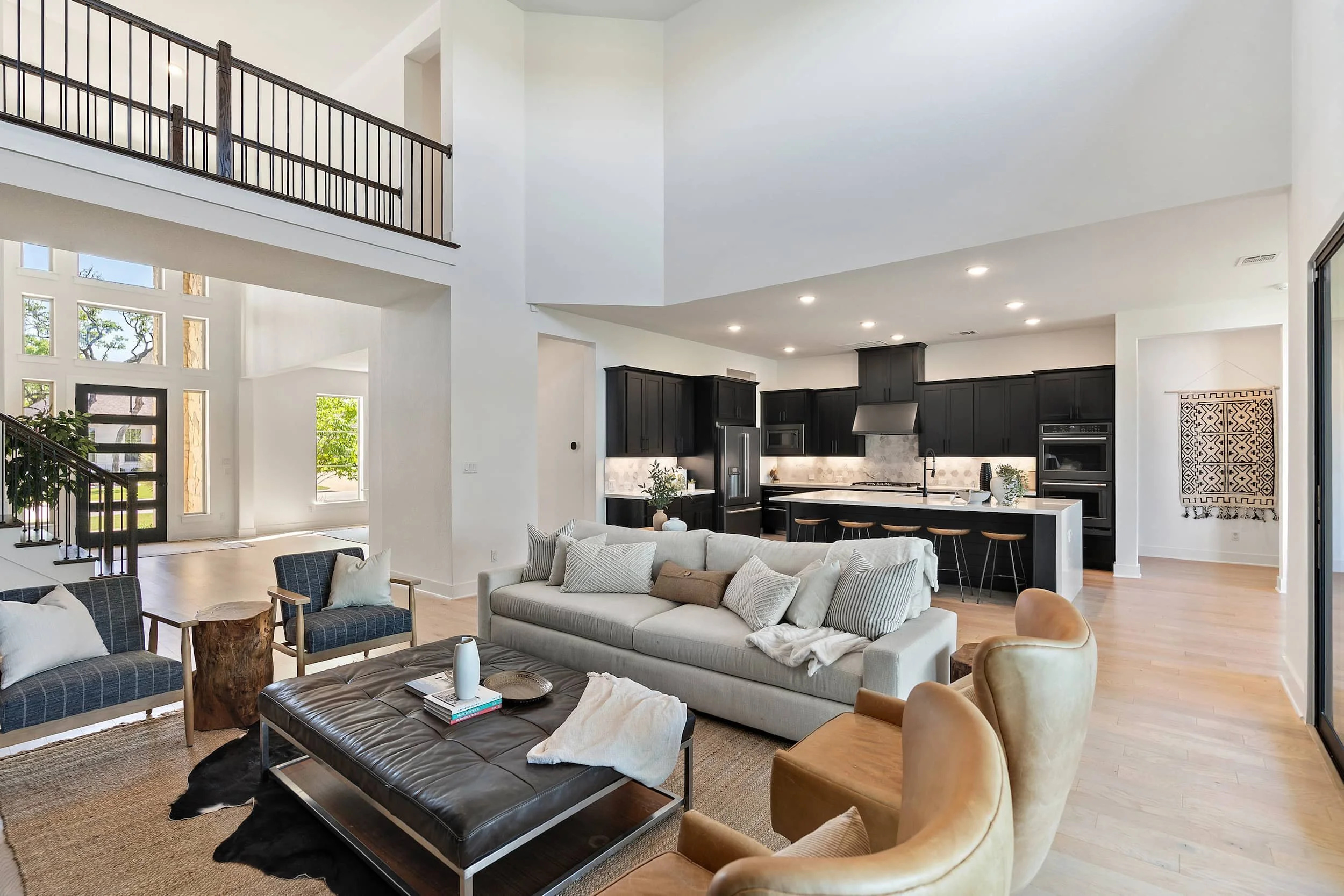 Austin open concept staging with living room and kitchen, black cabinets, neutral furniture, and high ceilings.