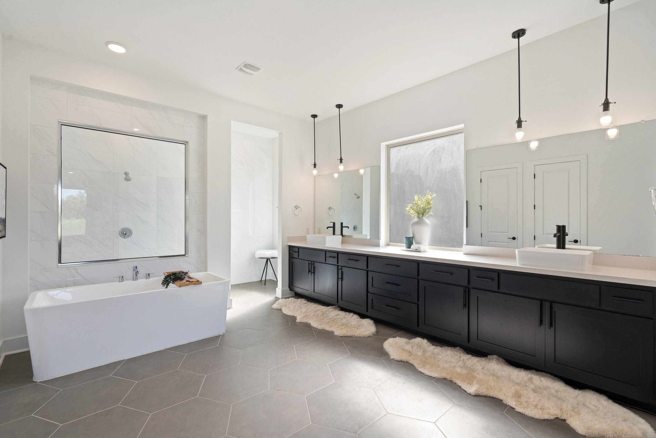Austin master bathroom with freestanding tub, dual vanity, black cabinets, hex tile flooring.