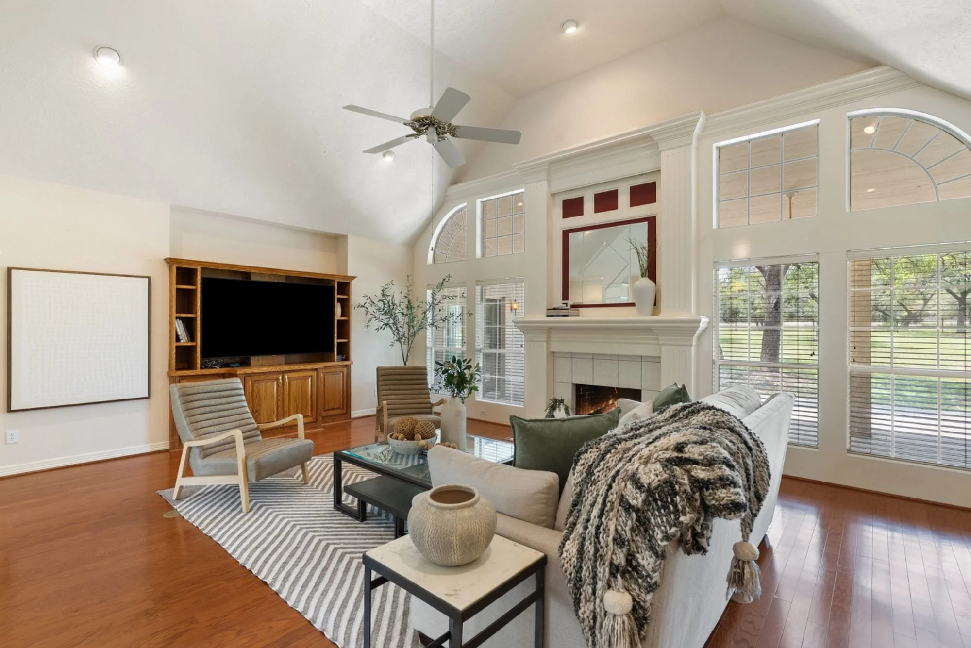Living room with a fireplace, built-in media center, and large windows overlooking the property.