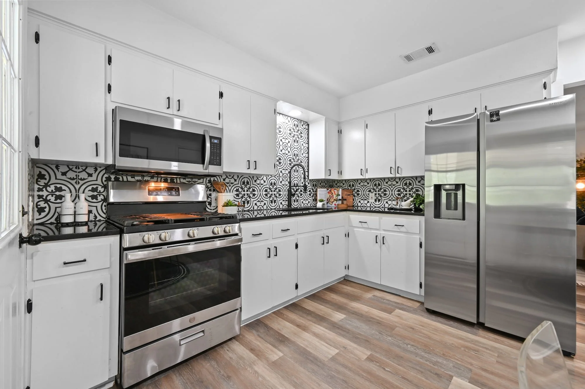 Crisp white cabinetry and a bold patterned tile backsplash frame this fully staged kitchen.