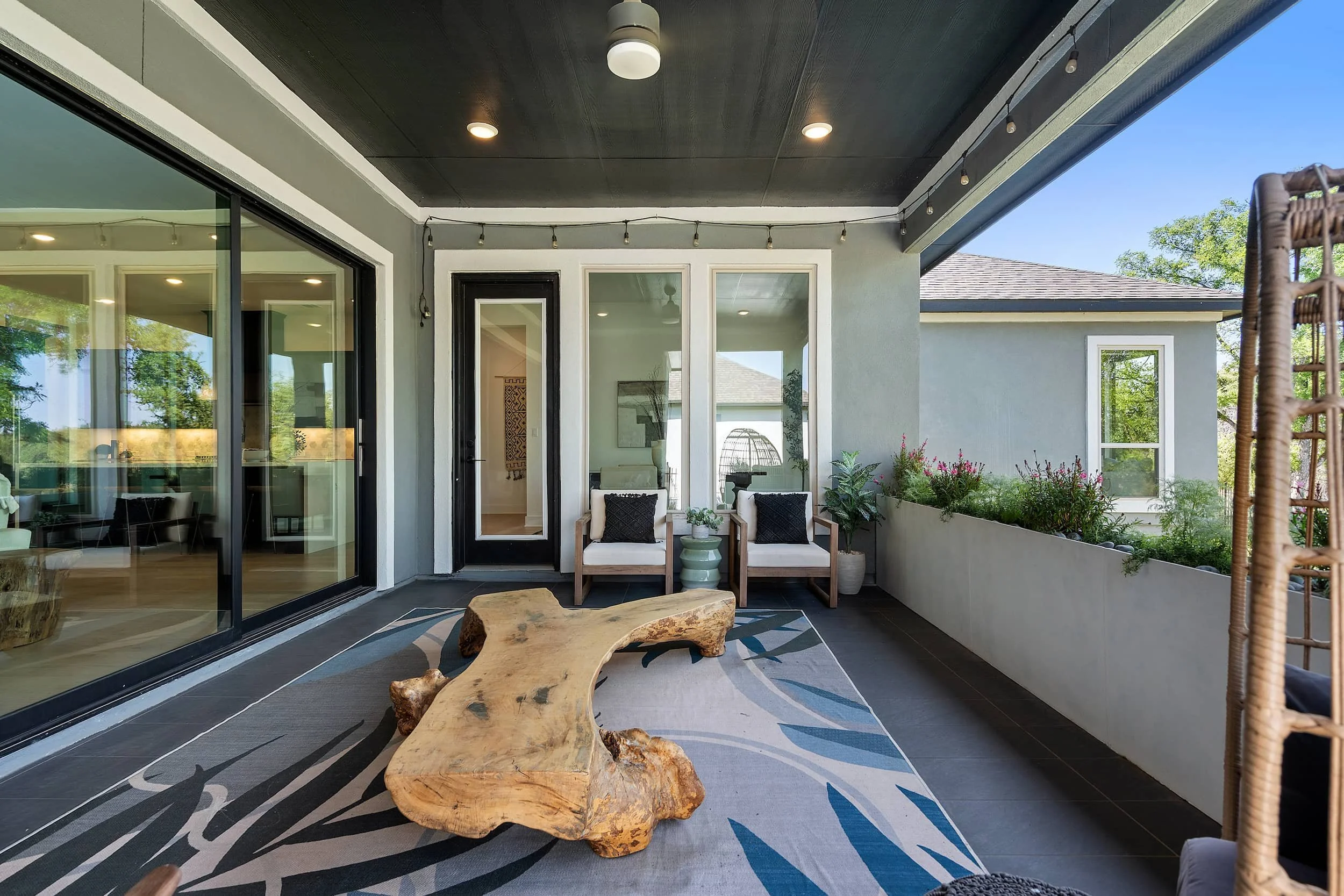 Luxury Austin outdoor living space featuring a live-edge wood table, black ceilings, and integrated concrete planters.