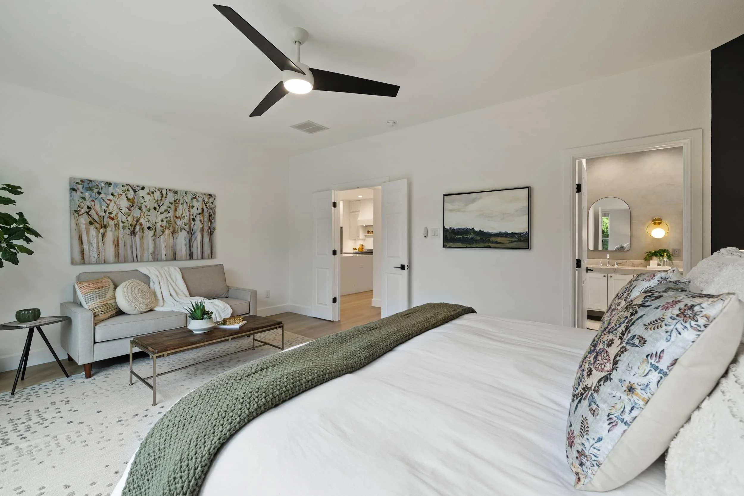 Master bedroom with small sofa with pillows and throw, small round table on one side, a rectangular table in front of it.