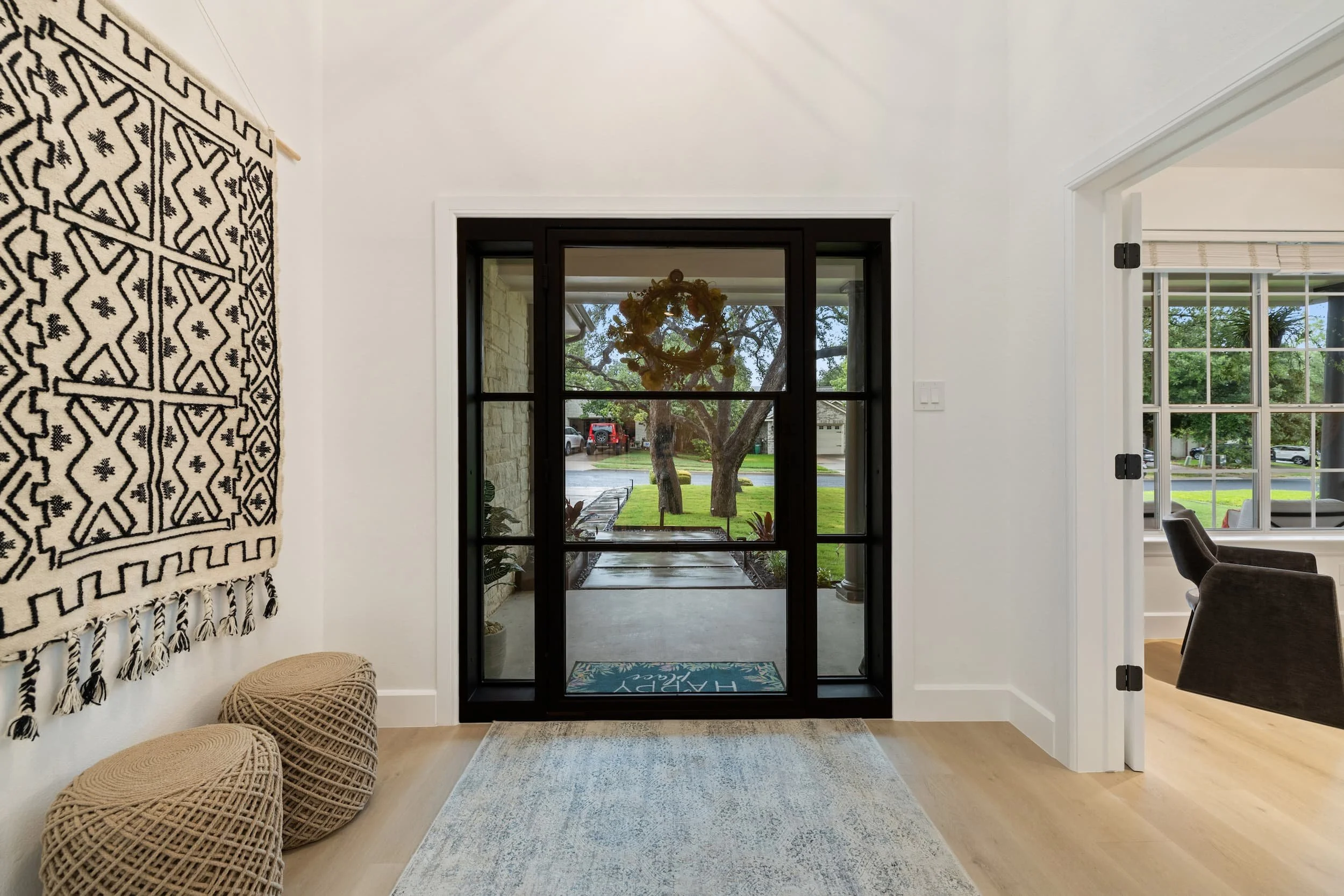 Bright entryway with vaulted ceiling, black-framed glass doors, and a view of the front yard.