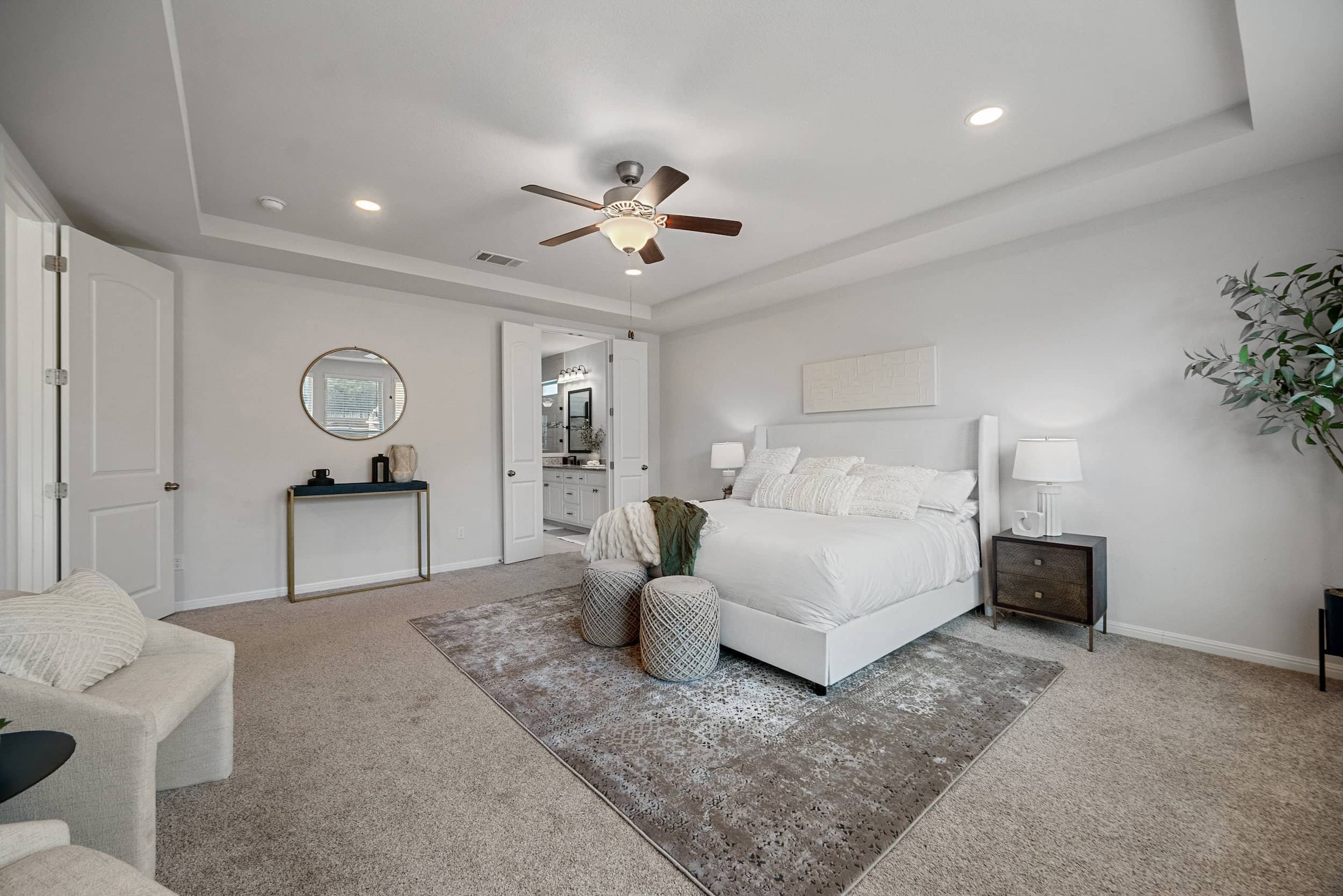 Austin modern staged bedroom featuring a large area rug, dark wood nightstands, and a view into the bright ensuite bathroom.