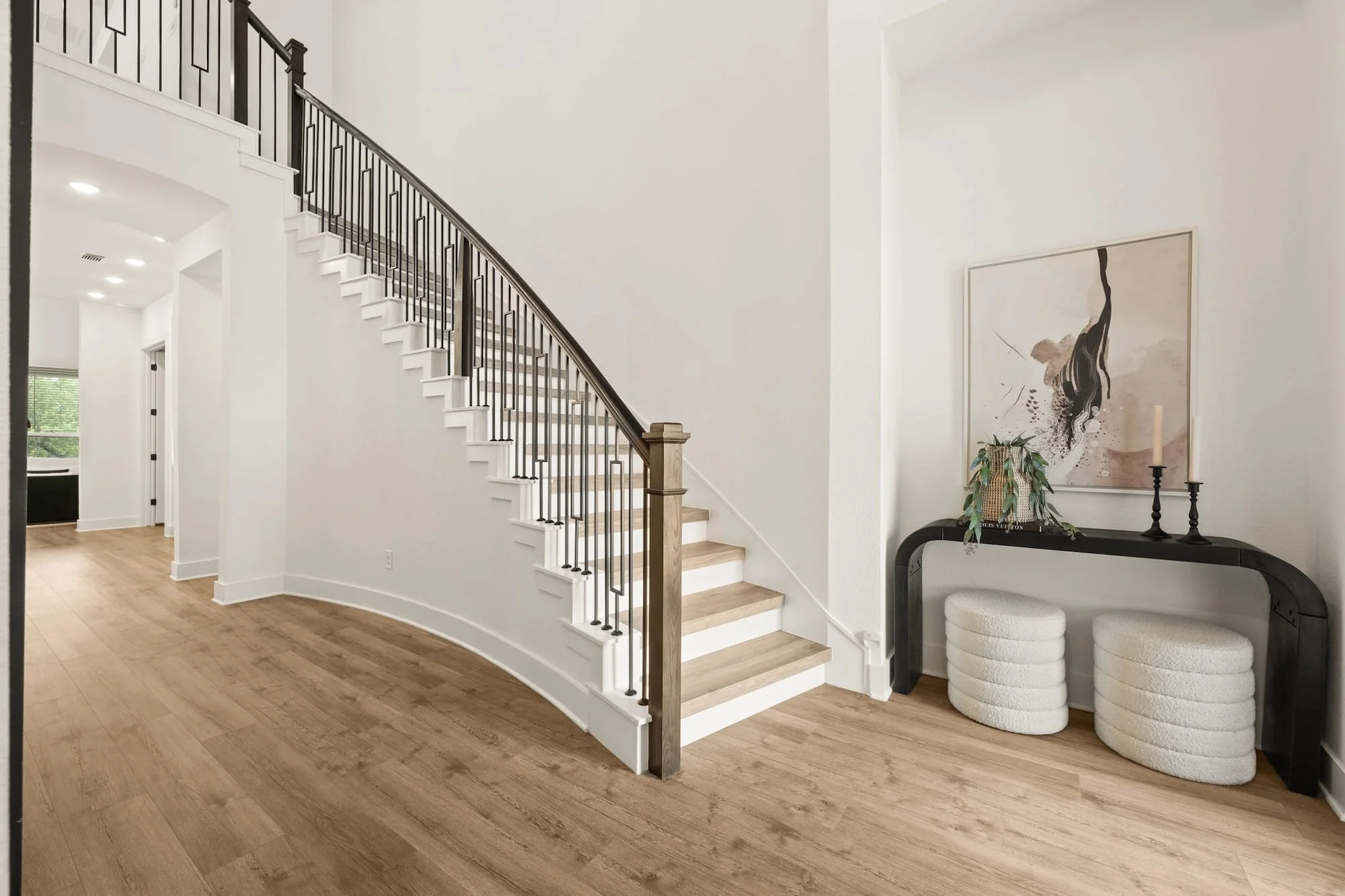 Dramatic curved staircase with custom iron railing, soaring entryway, and designer finishes