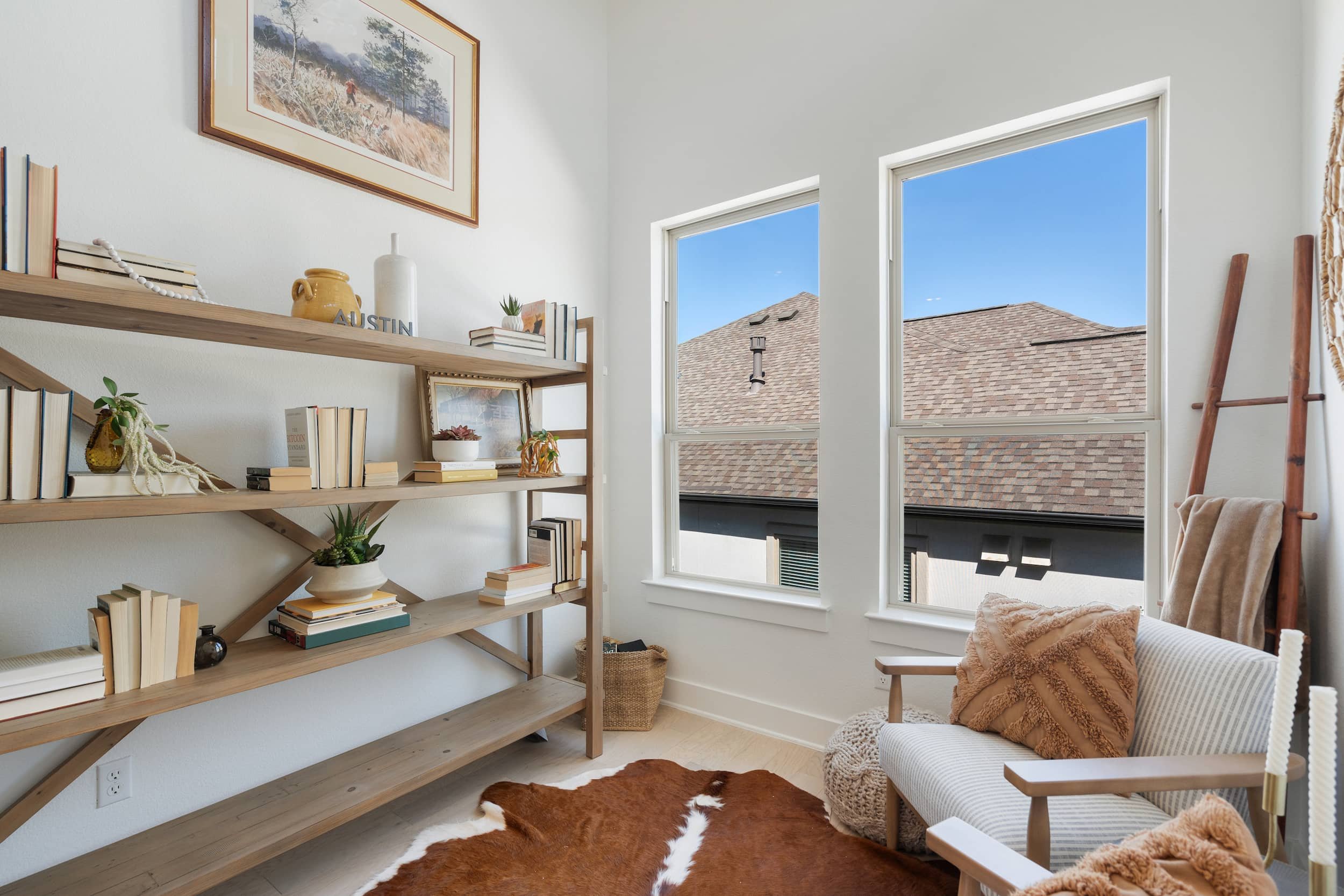 Cozy home office staged in Austin featuring open shelving, neutral tones, window light, styled decor.