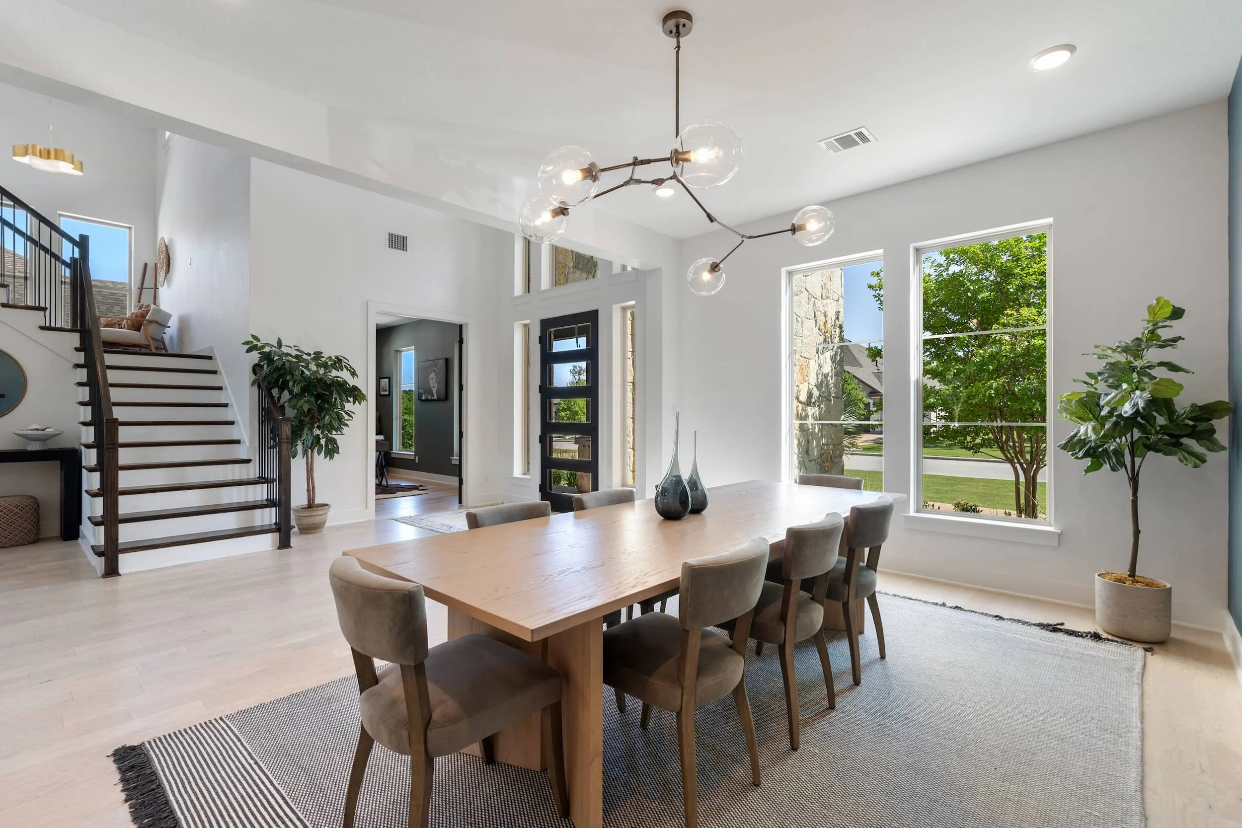 Real estate staging in Austin showcasing open dining space with wood furniture, glass chandelier, and bright layout.