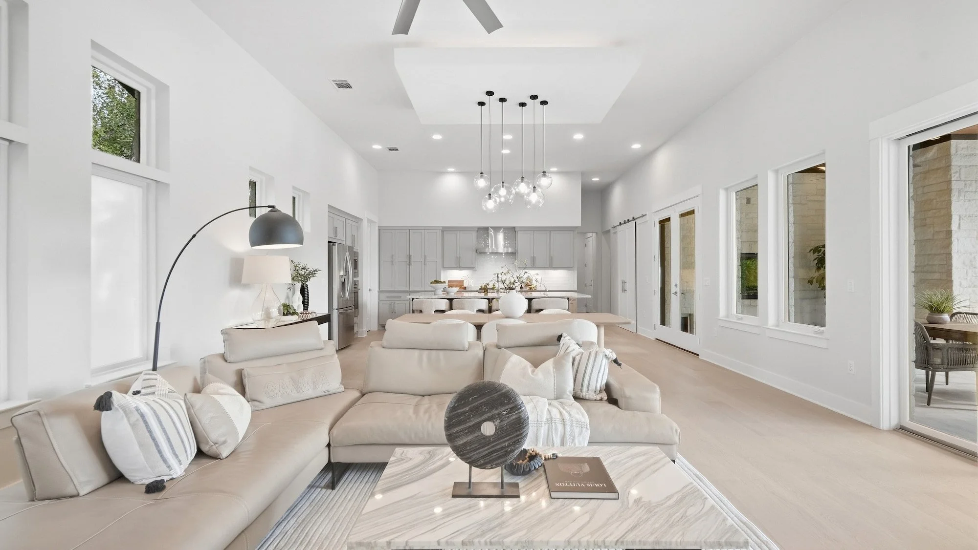Living room staged with a stone disc sculpture on a marble coffee table, looking toward the kitchen.