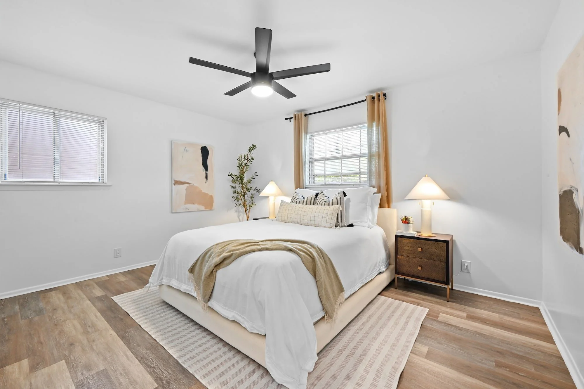 Tan curtains and matching bedside lamps frame this staged primary bedroom.