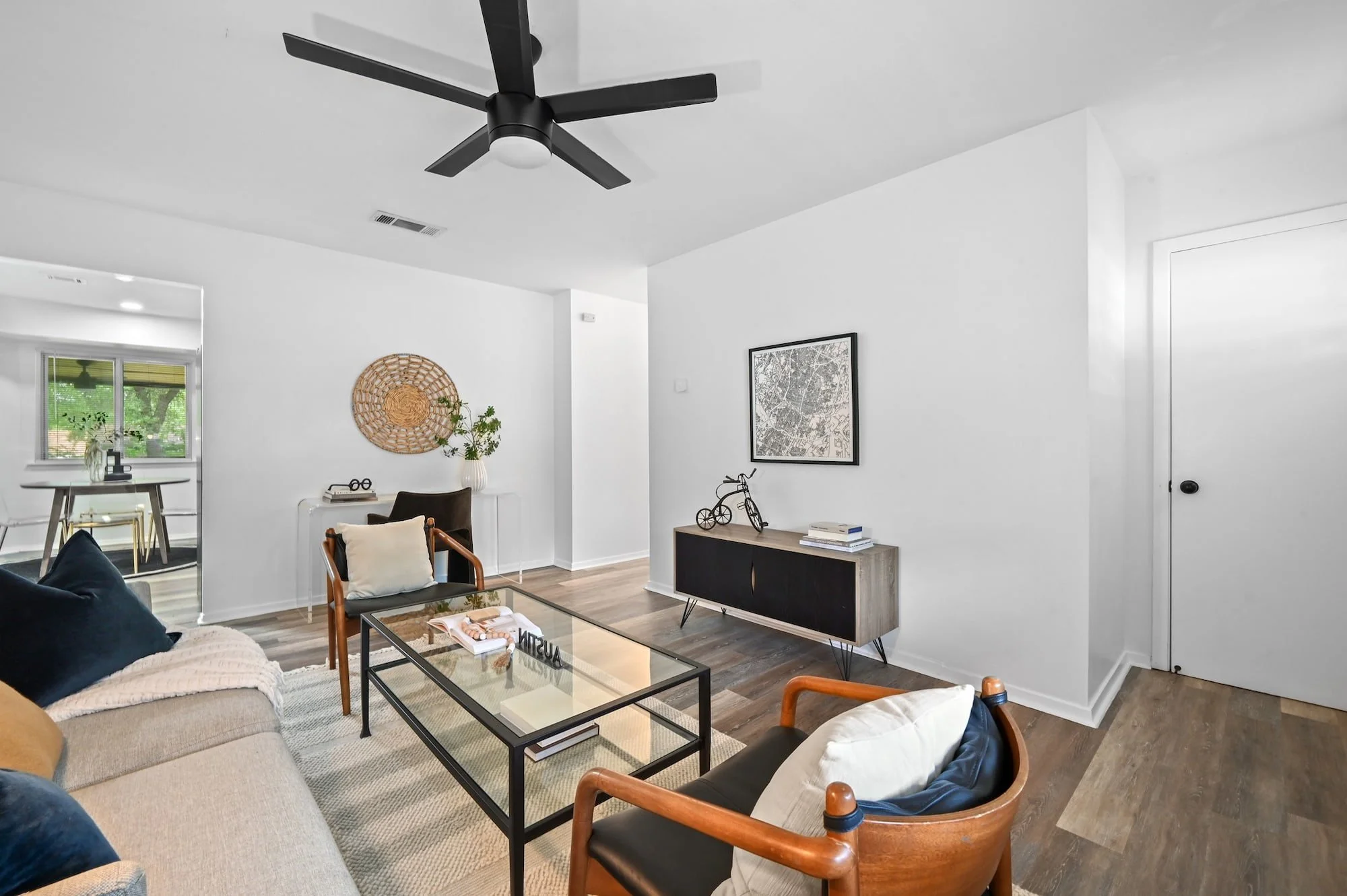 A media console and framed map art anchor this space, which opens into the dining nook.