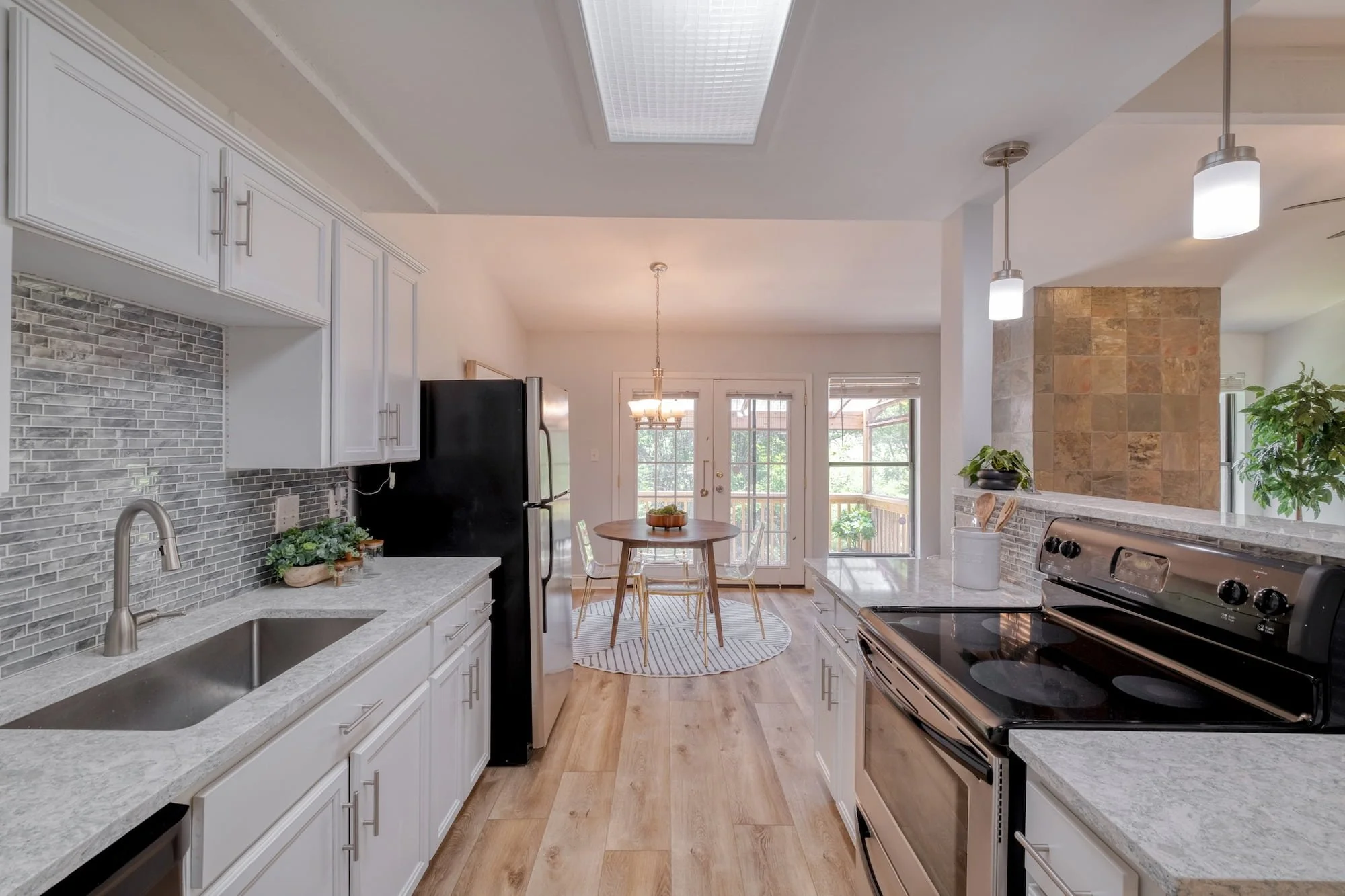 Updated galley kitchen in North Loop Austin with white cabinetry, breakfast nook, and deck access.
