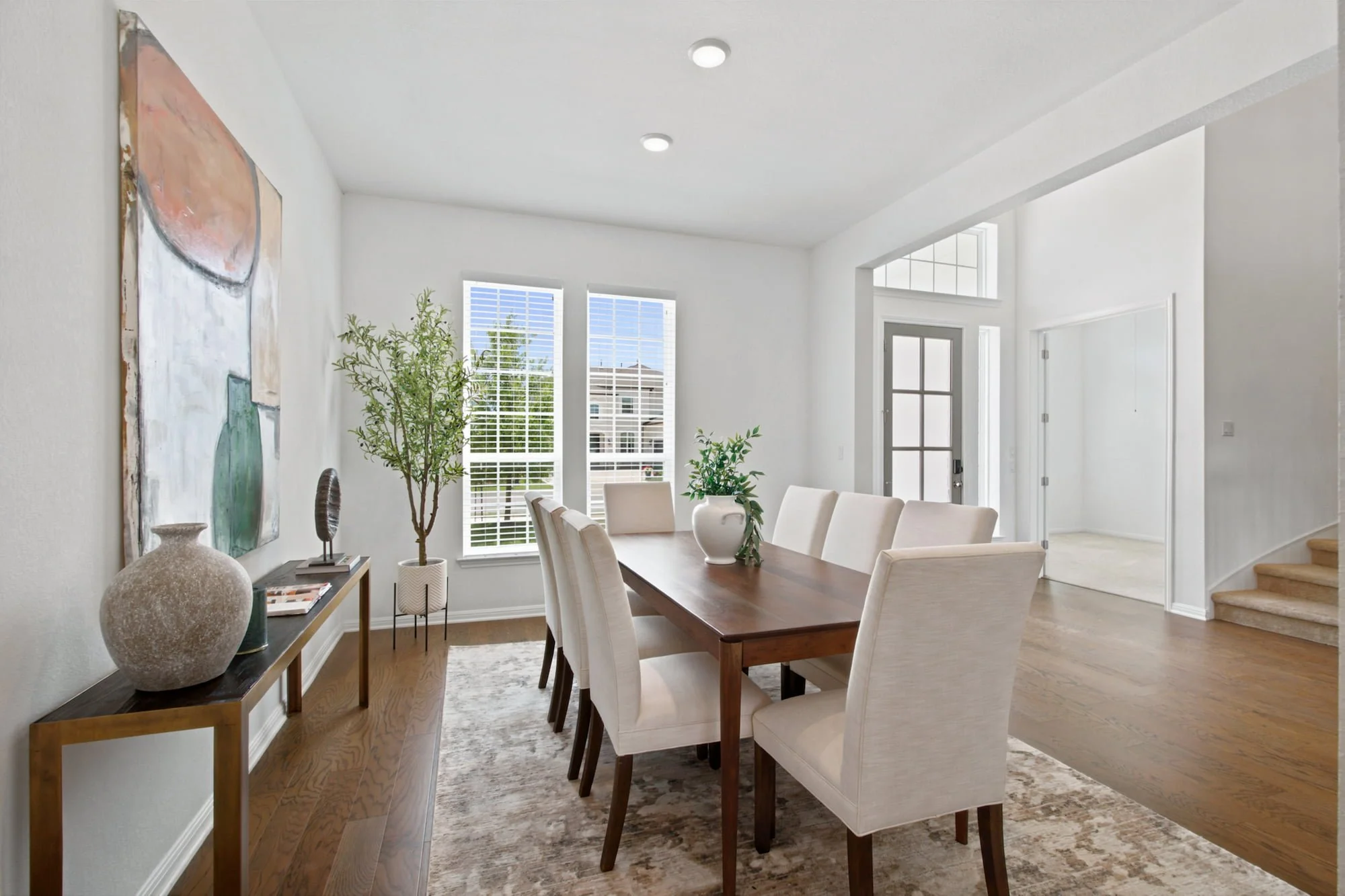 A rich wood table anchors the dining room, framed by soft linen chairs and layered art.