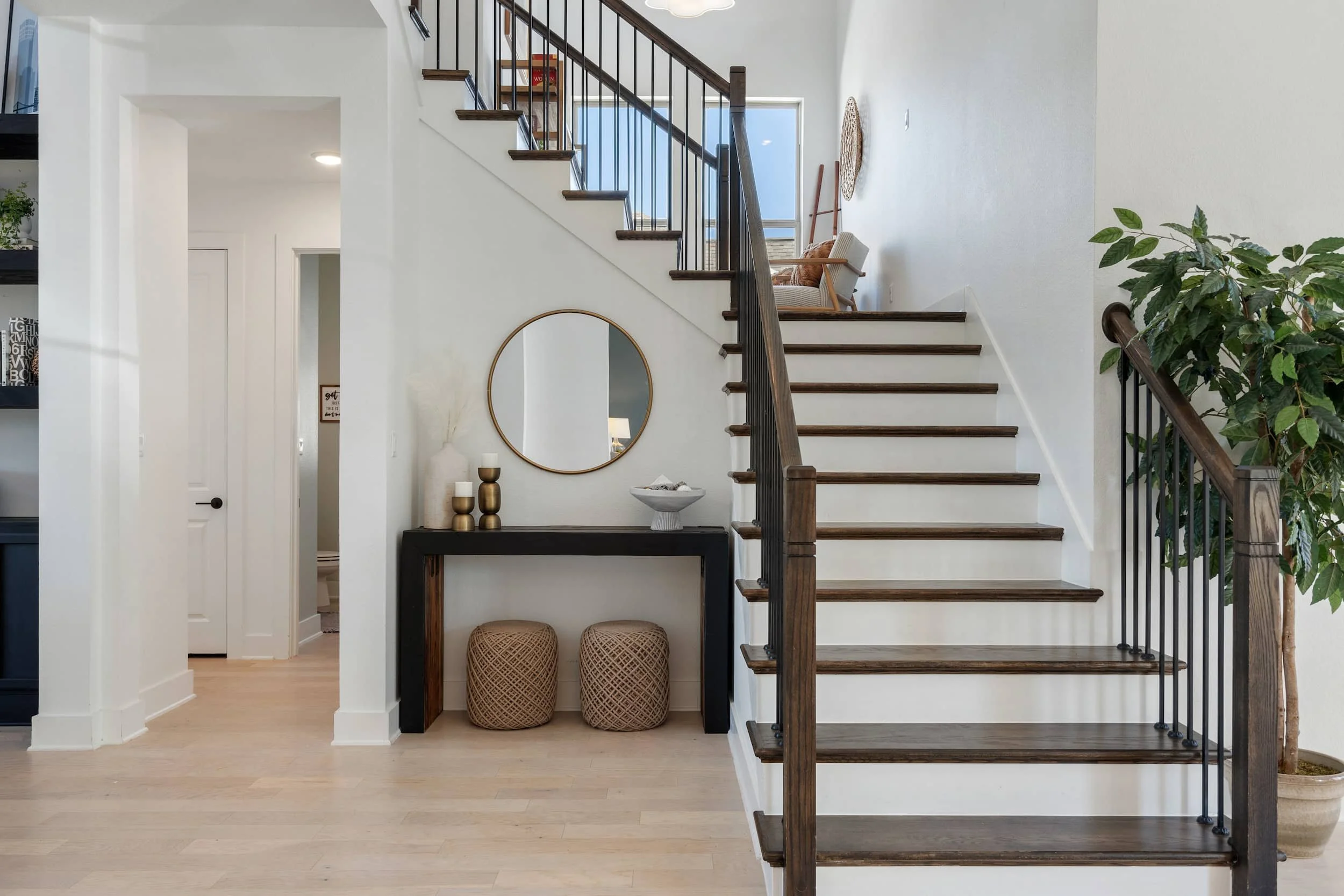 Modern staged foyer with wood stairs, iron balusters, console styling, neutral palette in Austin home staging interior design