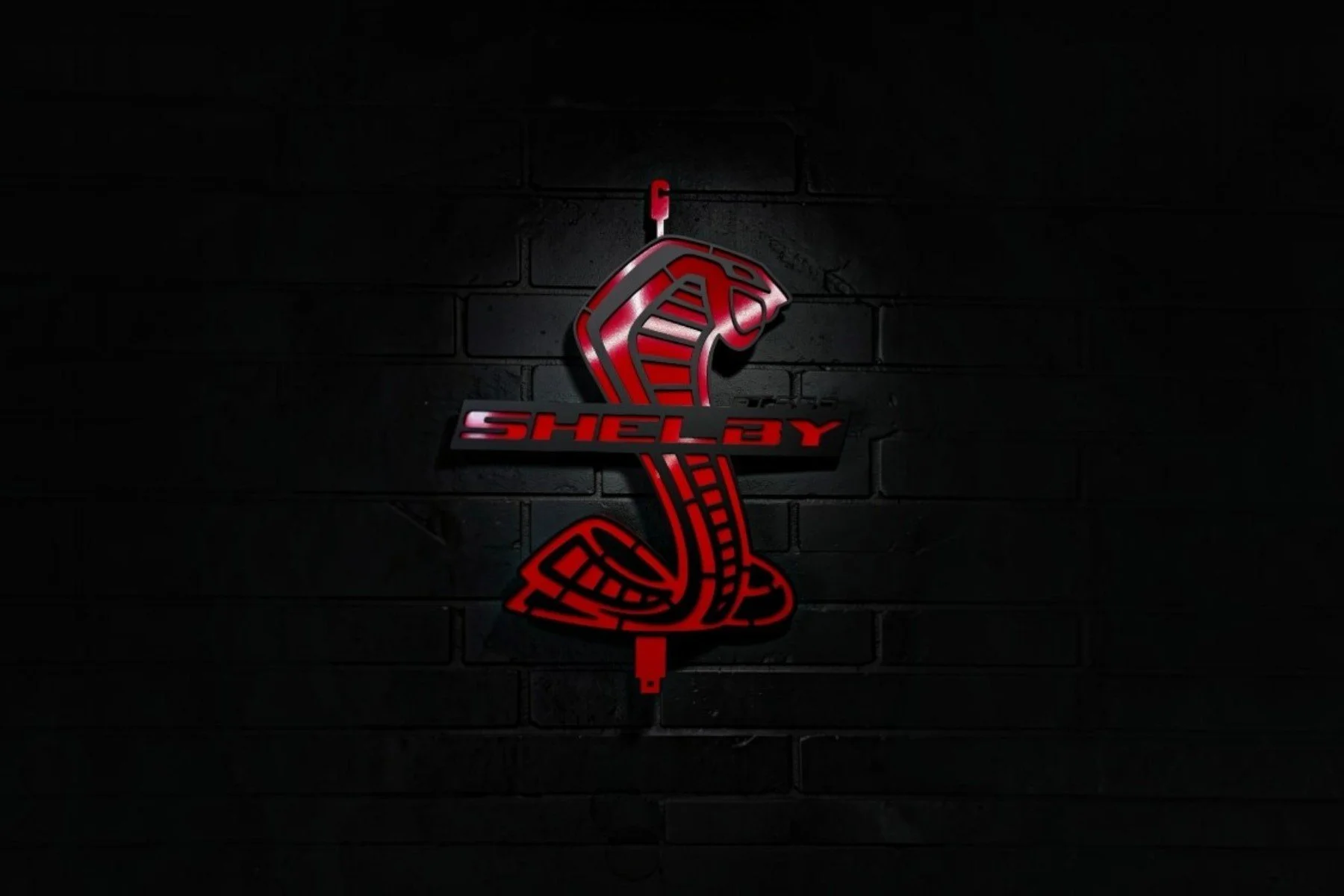 Neon sign of a red cobra snake with the word 'Shelby' in the middle, shaped like a snake coiled around a stick, mounted on a dark brick wall.