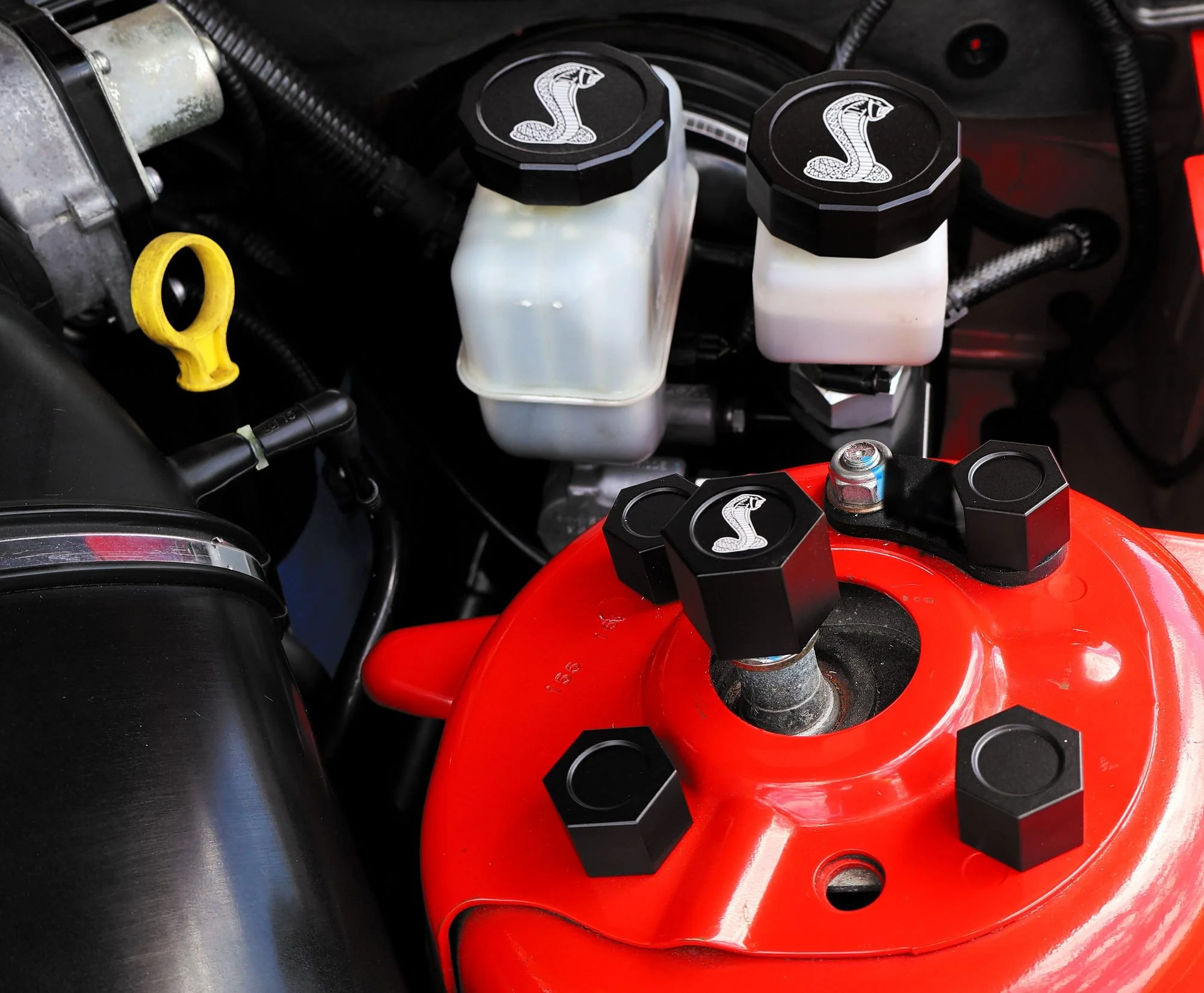 Black billet shock tower caps installed on the red shock tower of a Shelby GT500