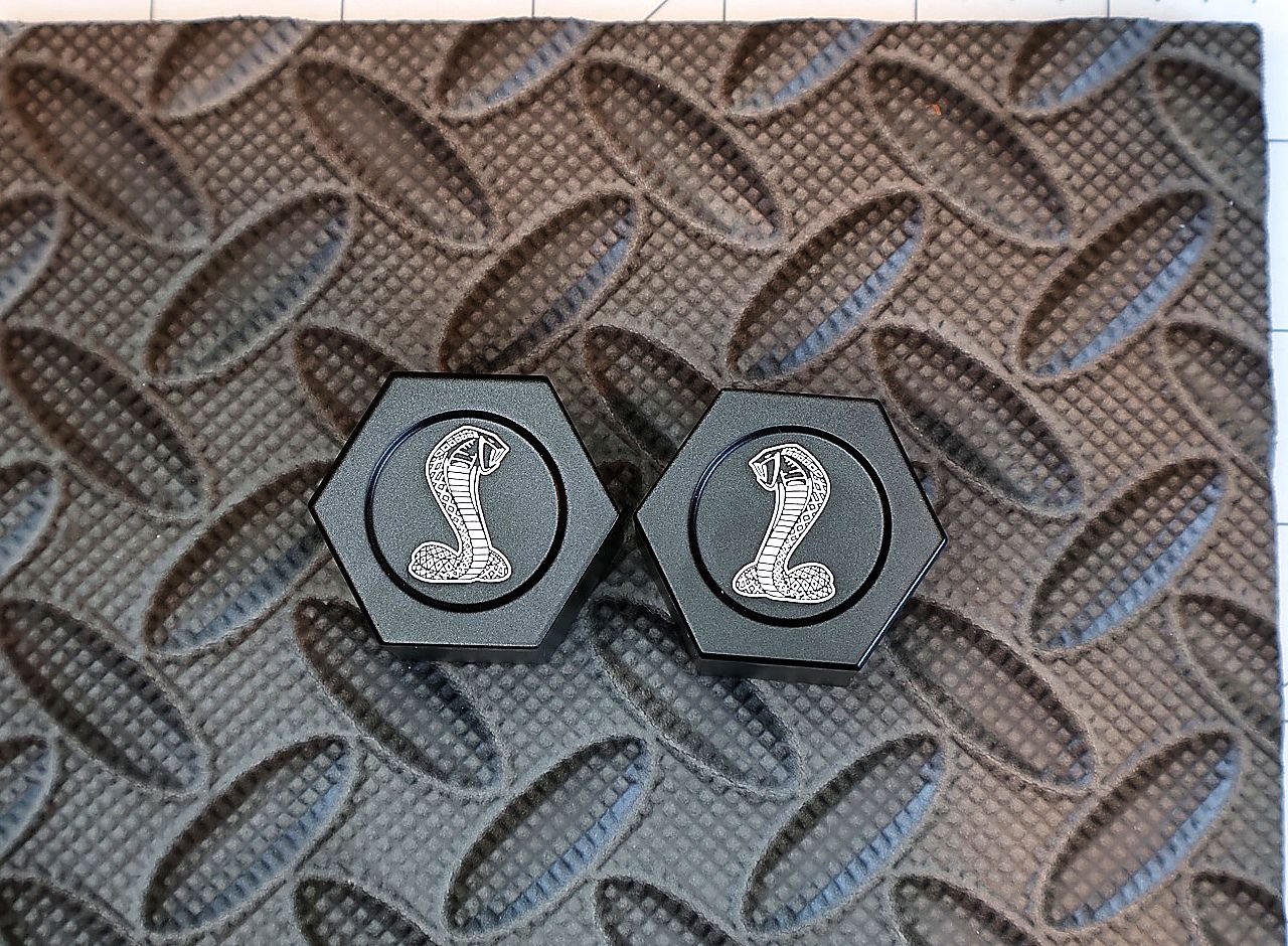 Two billet shock tower center caps laser engraved with a classic snake