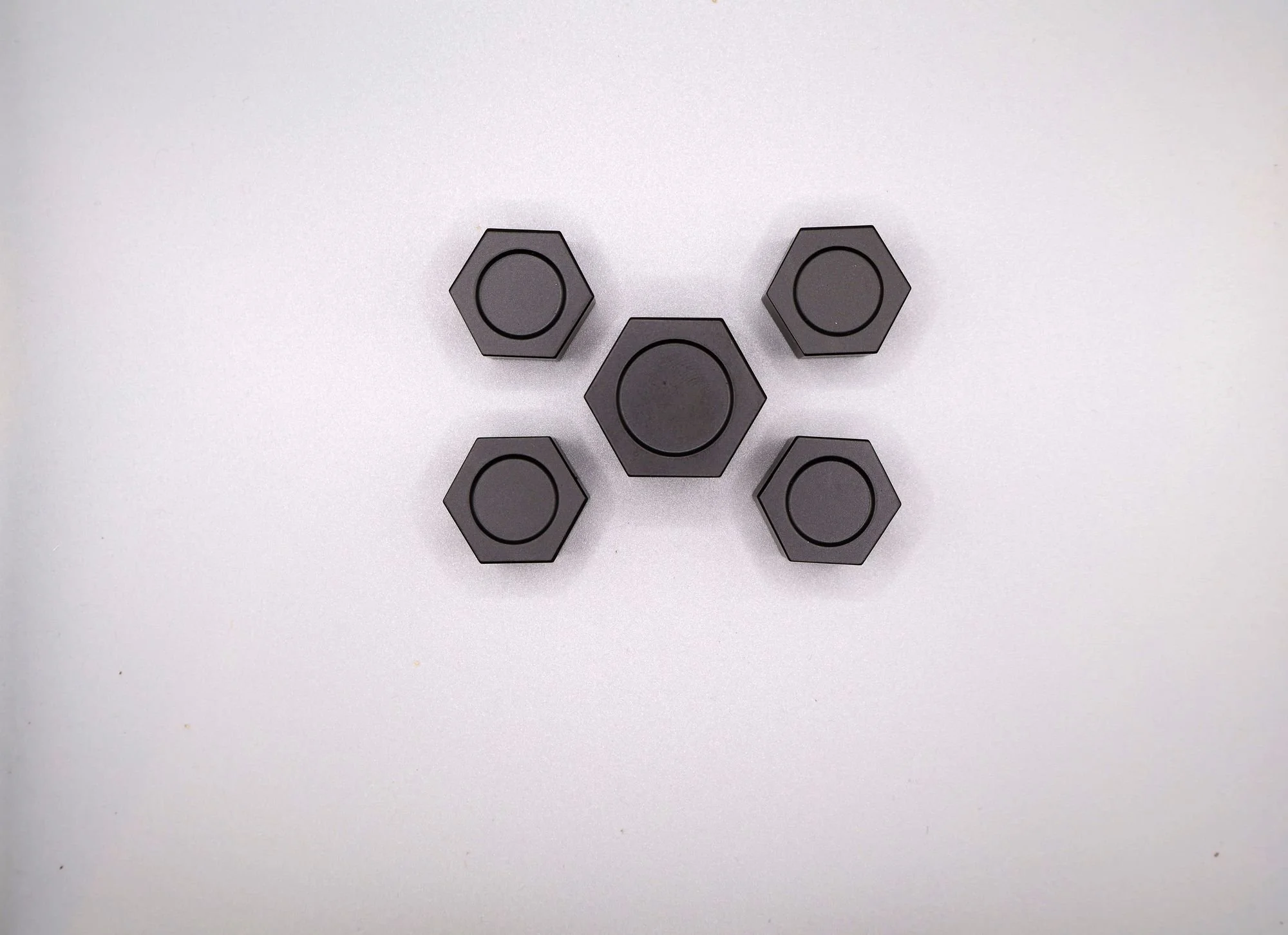 Overhead view of billet shock tower caps showing the 32 mm center cap beside 26 mm perimeter caps