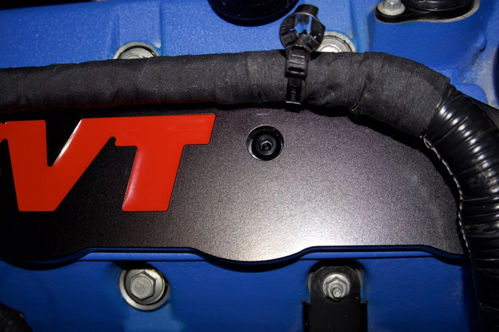Black titanium bolts installed on a billet coil cover