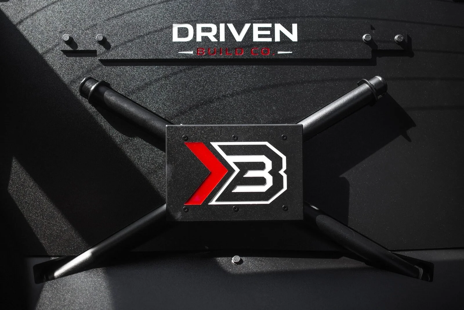 Overhead view of the EMP Parts X-brace seat delete panel showing the tubular X-brace and center badge