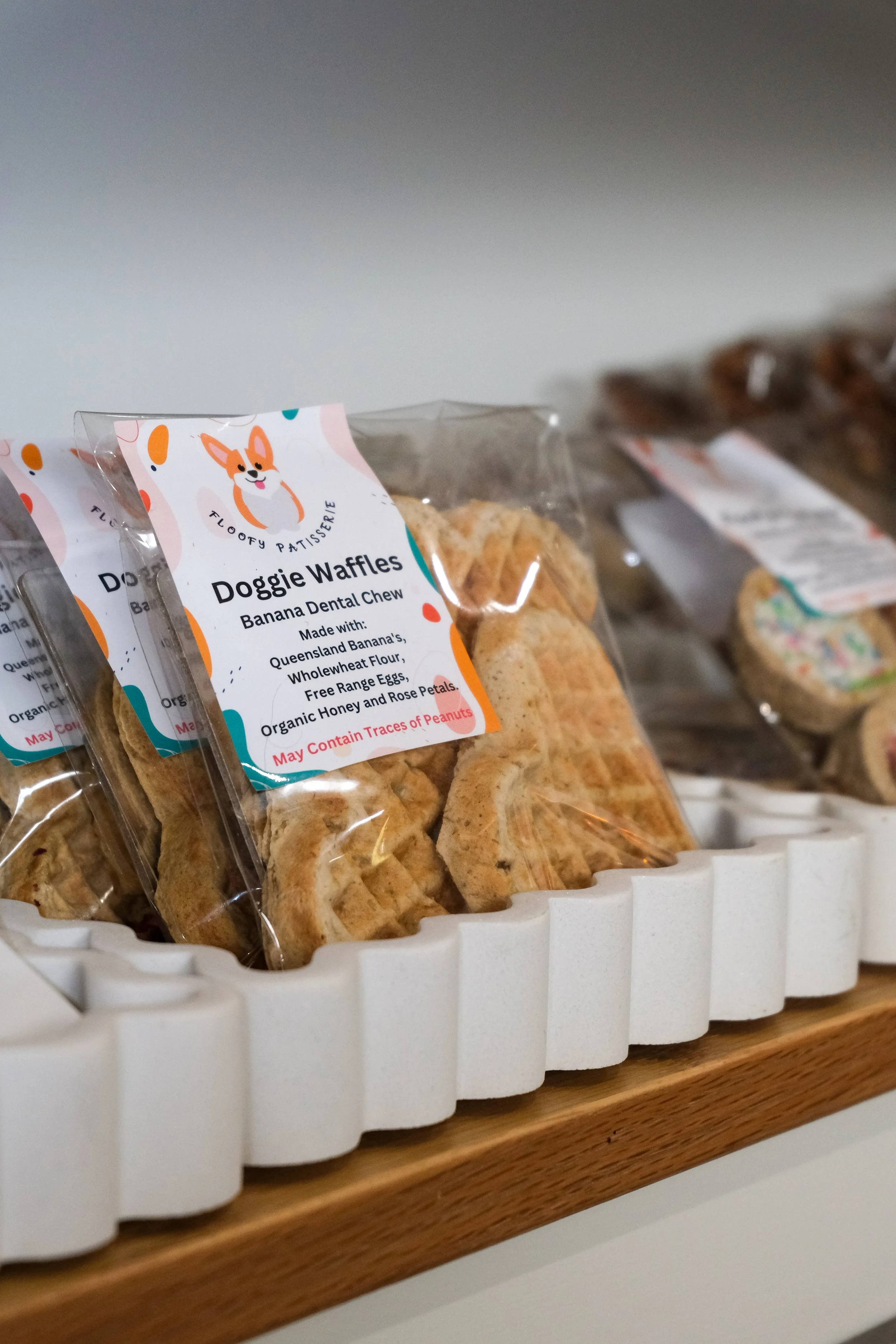 Packaged doggie waffles labeled 'Banana Dental Chew' on a wooden shelf.