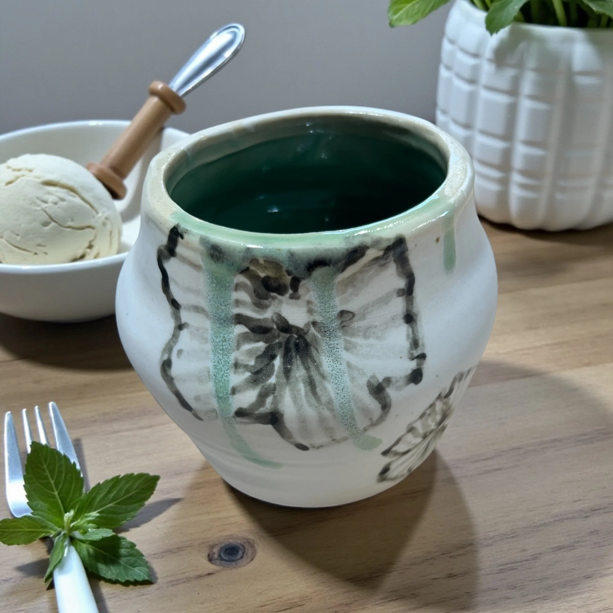 Ice white vase with black flowers with a mossy glossy green interior