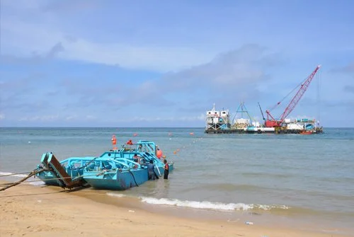 Jetting sled laying submarine cable ashore, with cable installation barge in the background