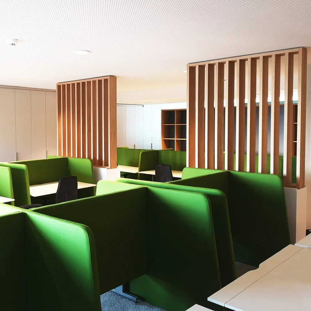 Modern interior space with green booth seating and wooden room dividers.