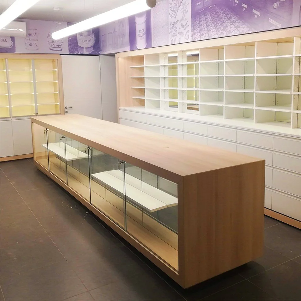 Empty retail display case with glass doors in a store with empty shelves and purple wall decorations.