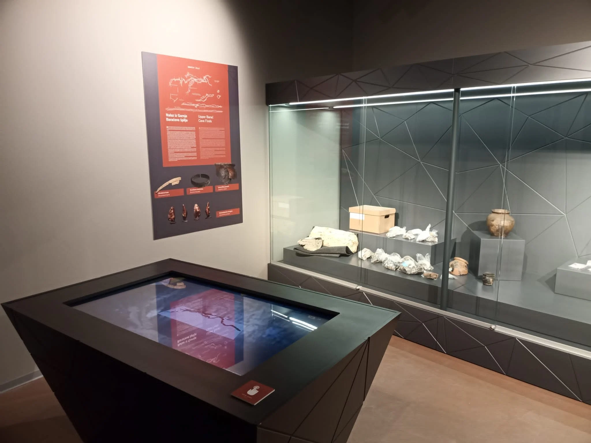 Museum exhibit with a display case containing rocks and artifacts, and an informational poster on the wall.