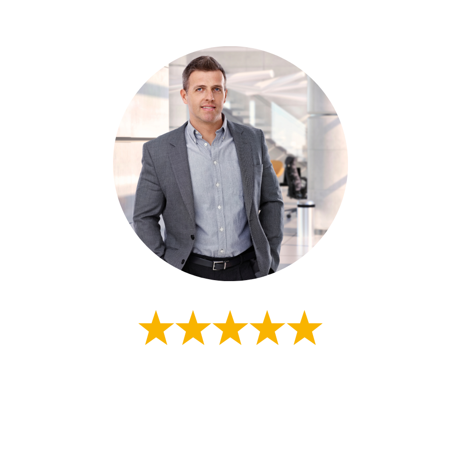Businessman in a gray blazer and light blue shirt standing in an airport terminal.