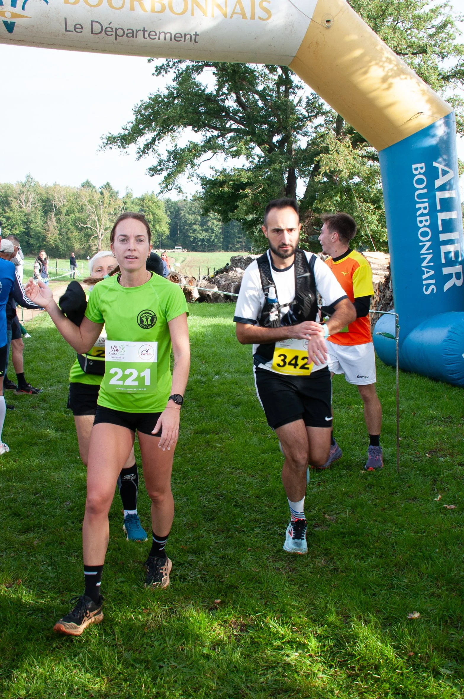 Des coureurs en tenue de sport passant la ligne d'arrivée sous une arche gonflable bleue avec le texte "ALIER BOURBONNAIS".