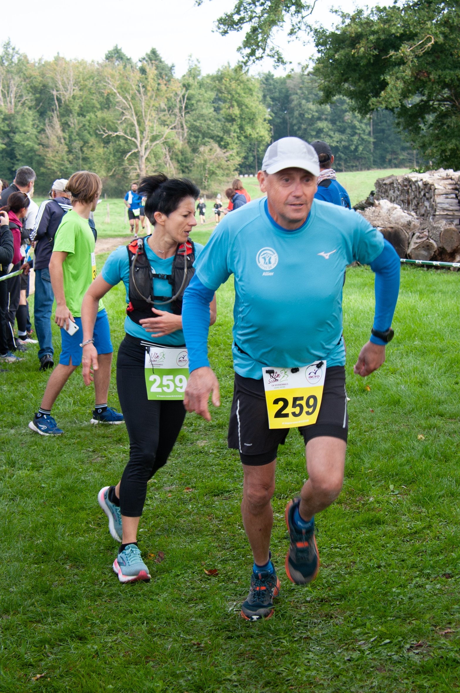 Des coureurs participent à une course en plein air, portant des dossards avec le numéro 259, sur une piste herbeuse entourée de nature.